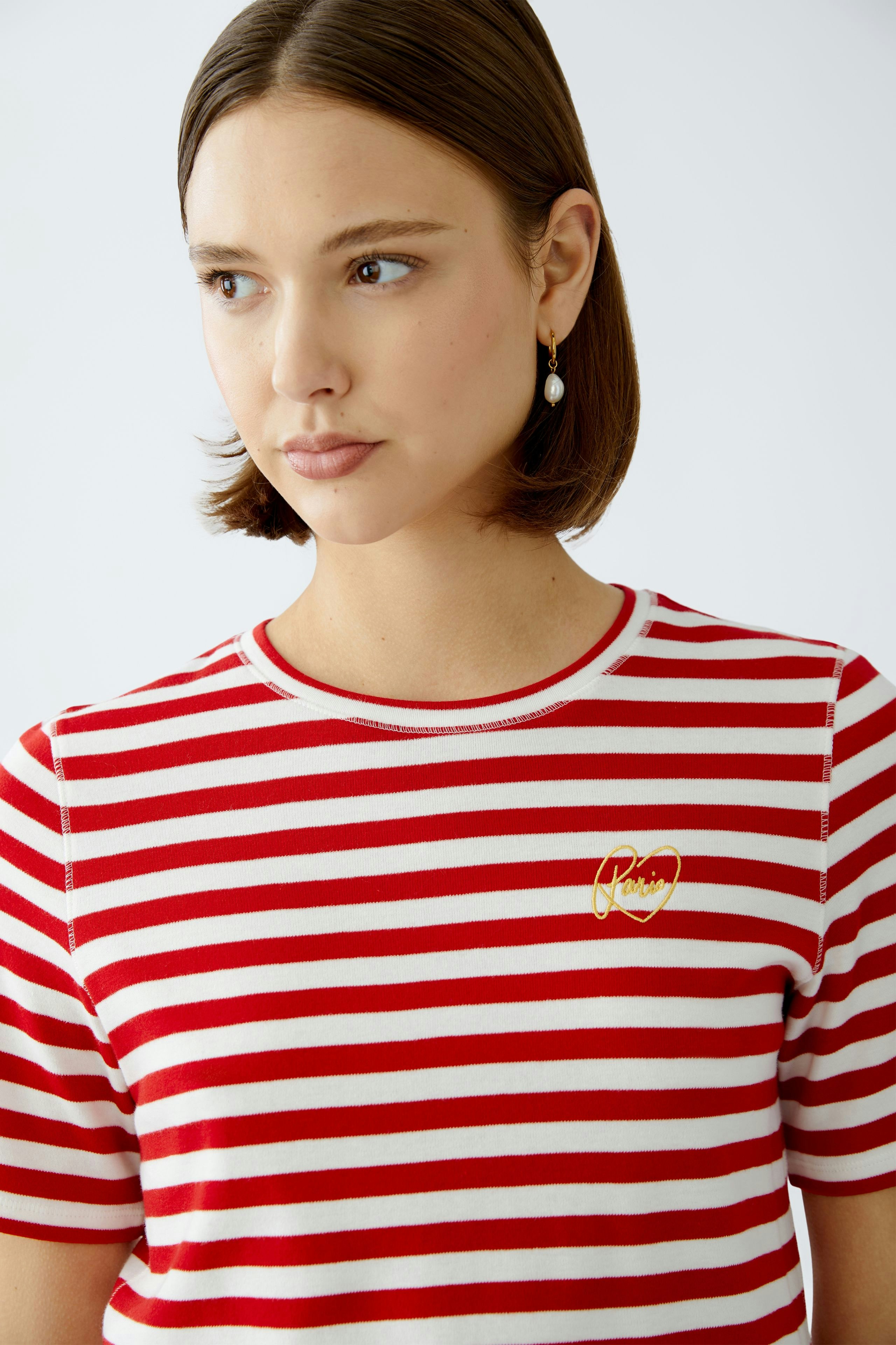 Stylish women's T-shirt: A woman in a red and white striped tee with a gold logo.