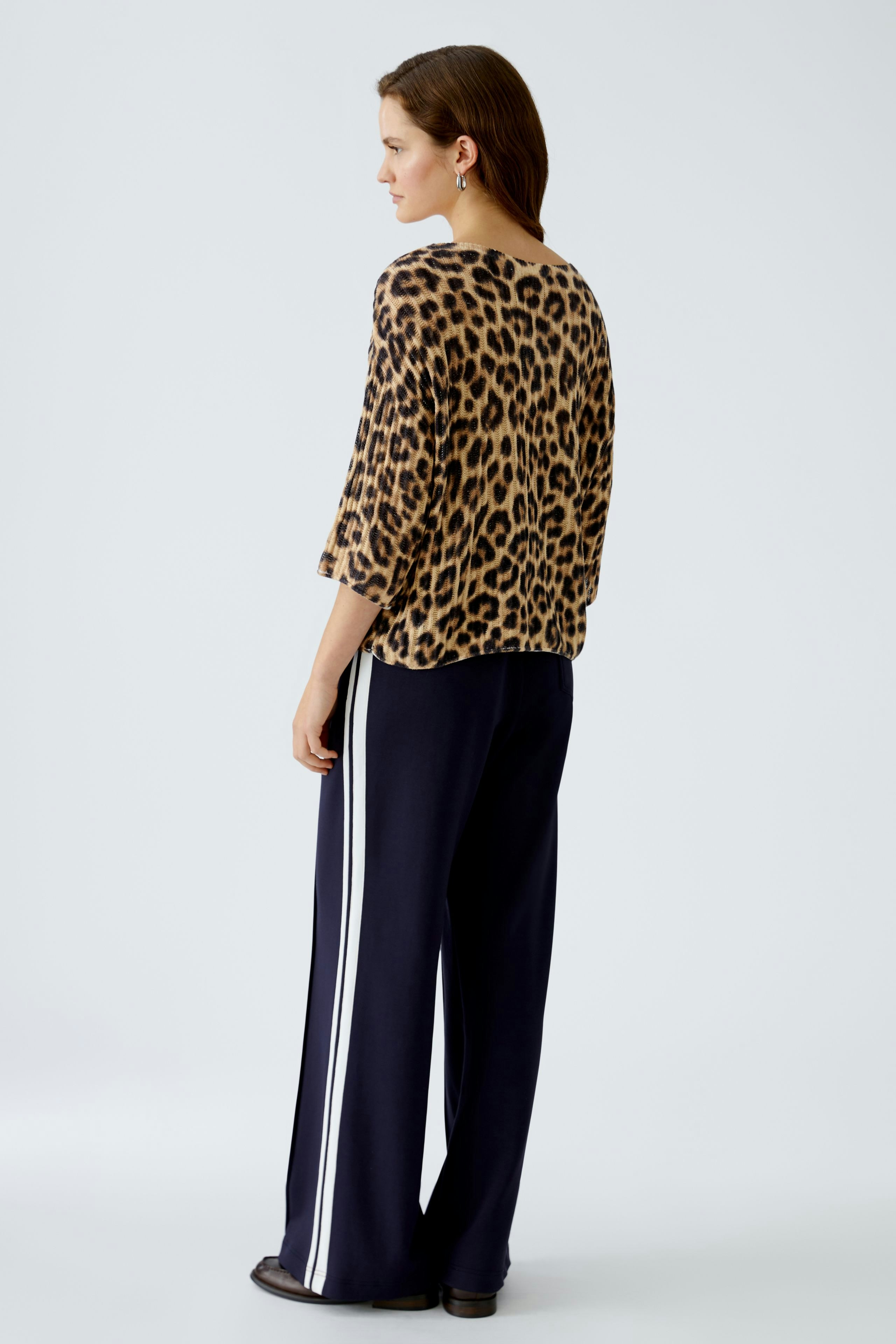 Stylish women's pullover: A woman in a leopard print pullover and navy pants, showcasing a trendy look.
