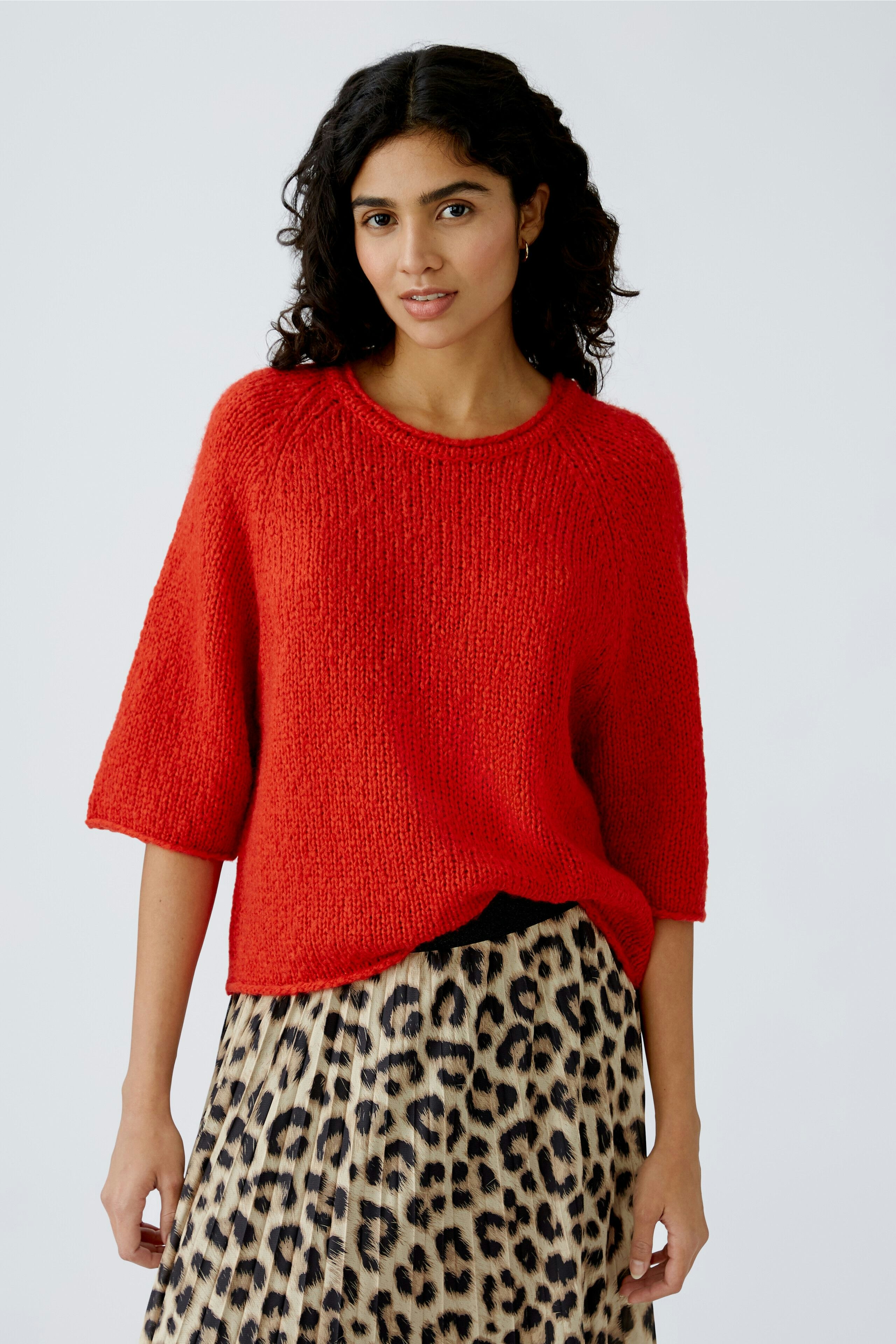Roter Damen-Pullover: Frau trägt einen lässigen, strukturierten Pullover zu einem Leopardenrock.