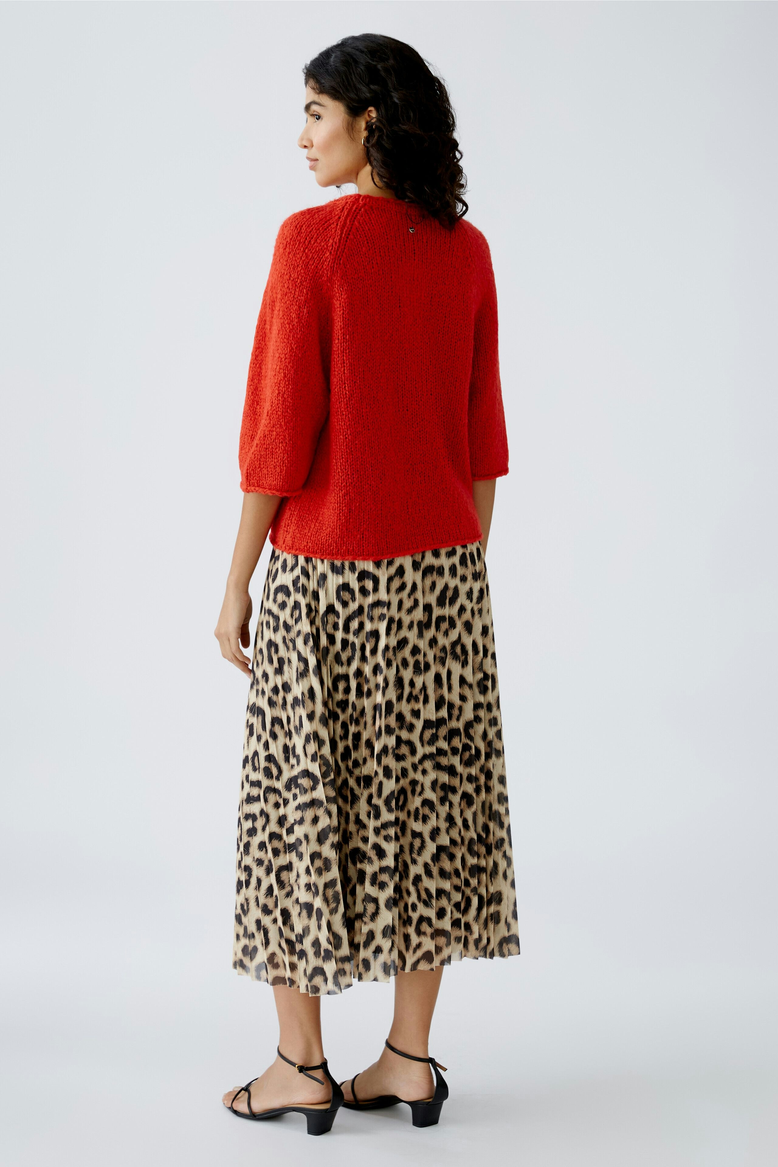 Damen-Pullover: Frau in rotem, lässigem Pullover mit 3/4-Ärmeln und tierischem Printrock.