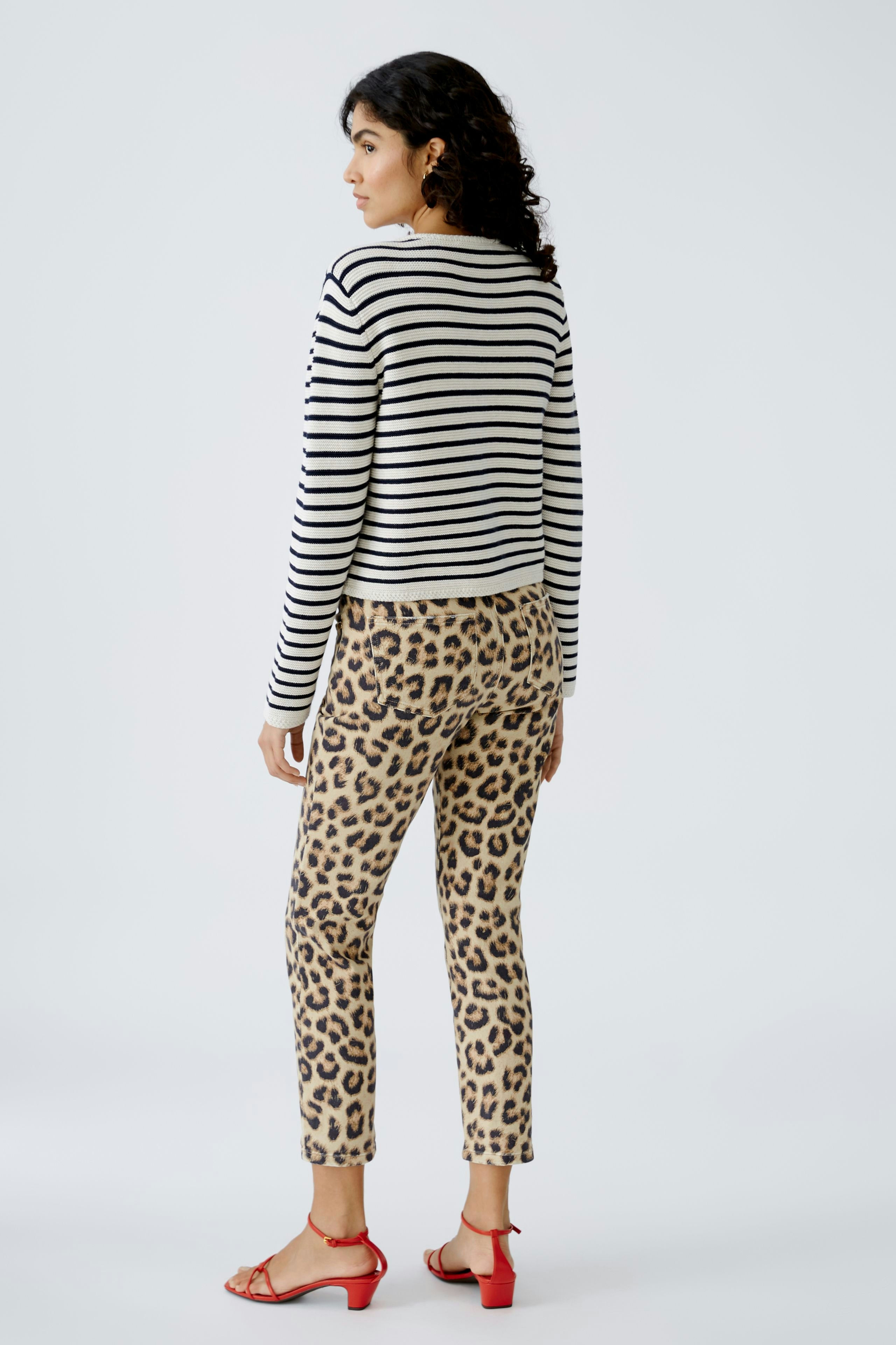Damen-Strickjacke: Frau in gestreifter Strickjacke mit lässigen Hosen im Leopardenmuster von hinten.