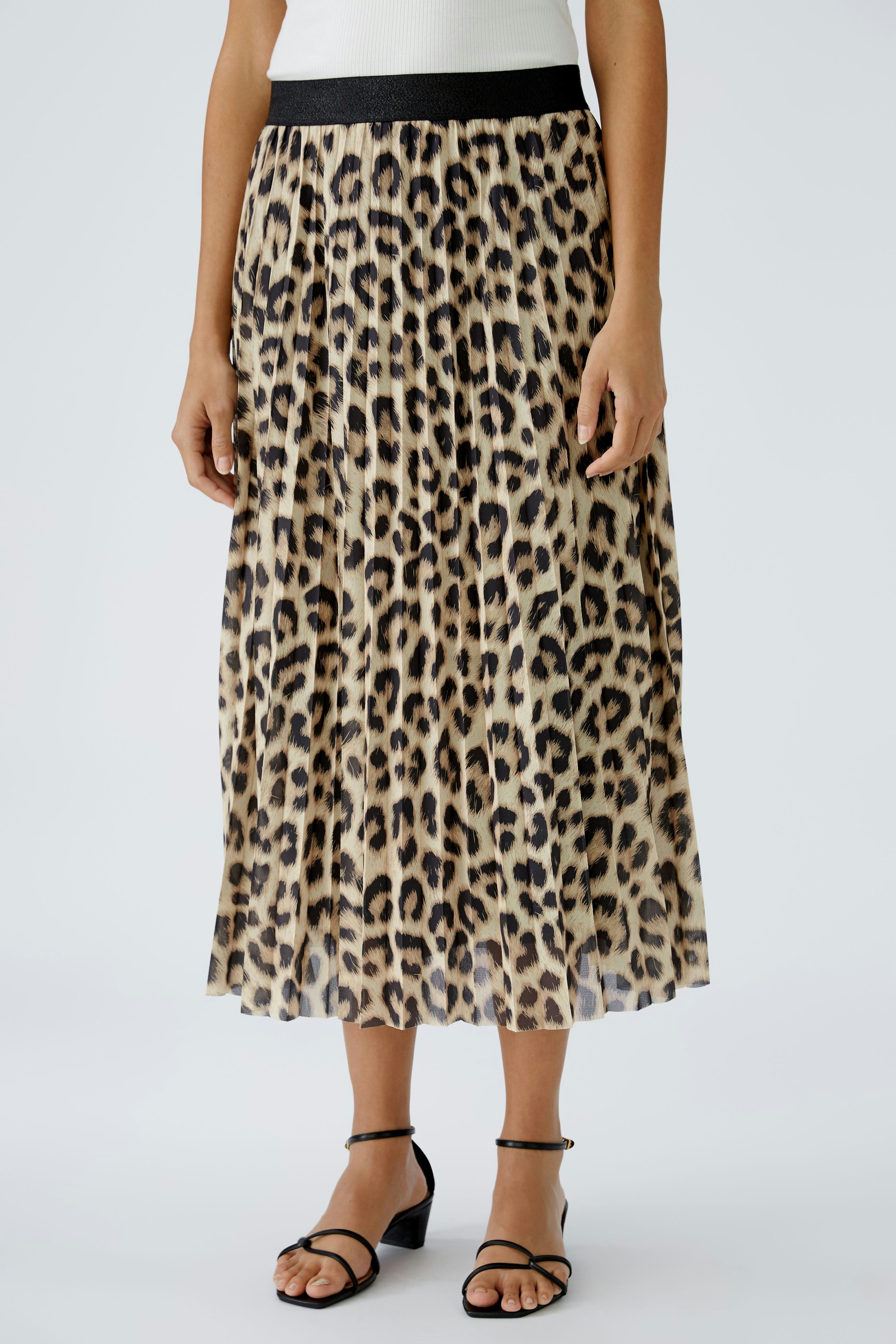 A-Linien-Rock: Elegante Frau trägt einen langen, plissierten Rock mit Leopardenmuster und schwarzem Bund.