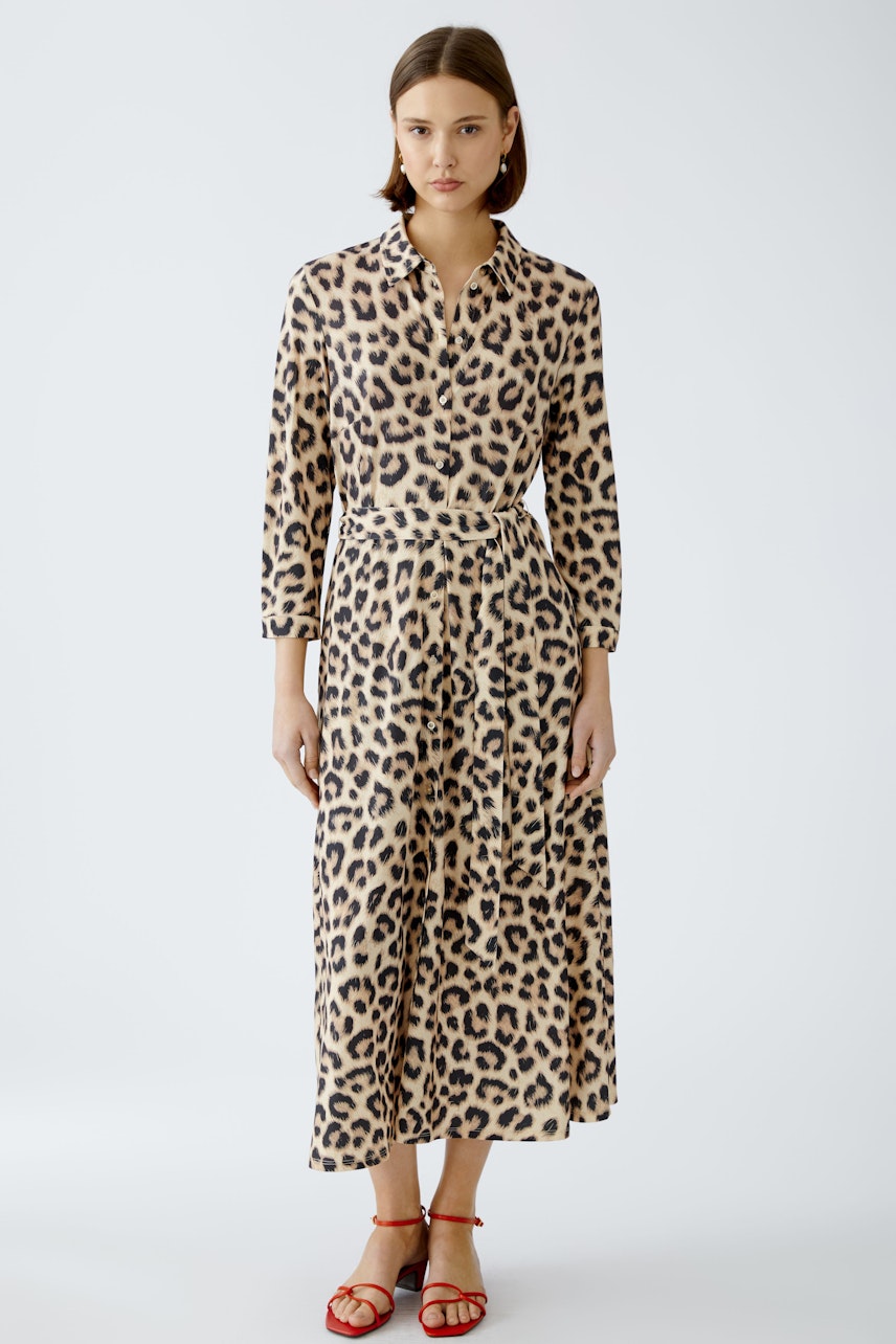 Stylish shirt dress: A woman in a leopard print shirt dress with a belted waist, exuding elegance.