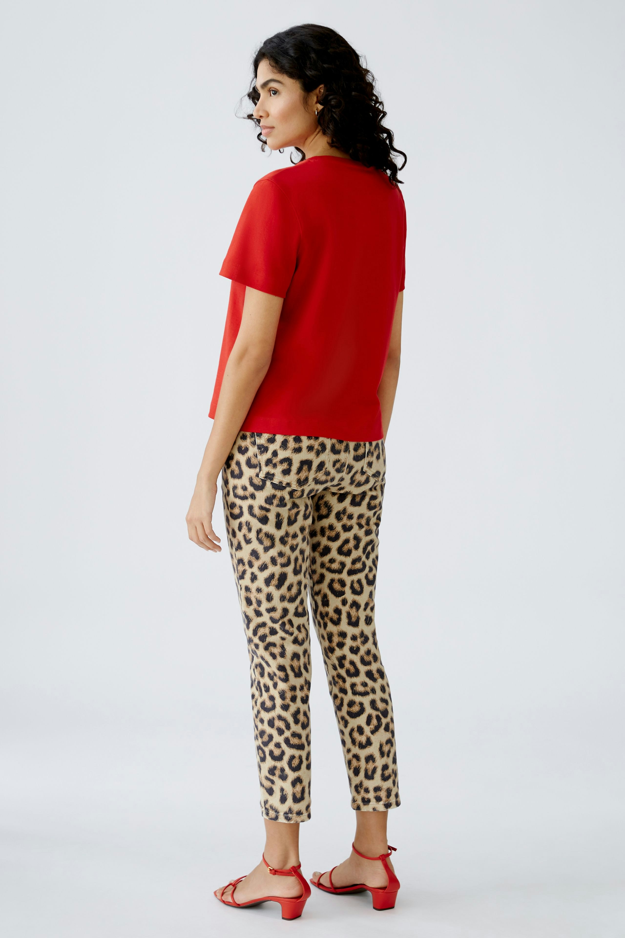 Stylish women's T-shirt: A woman in a red T-shirt and leopard print pants, showcasing a modern look.