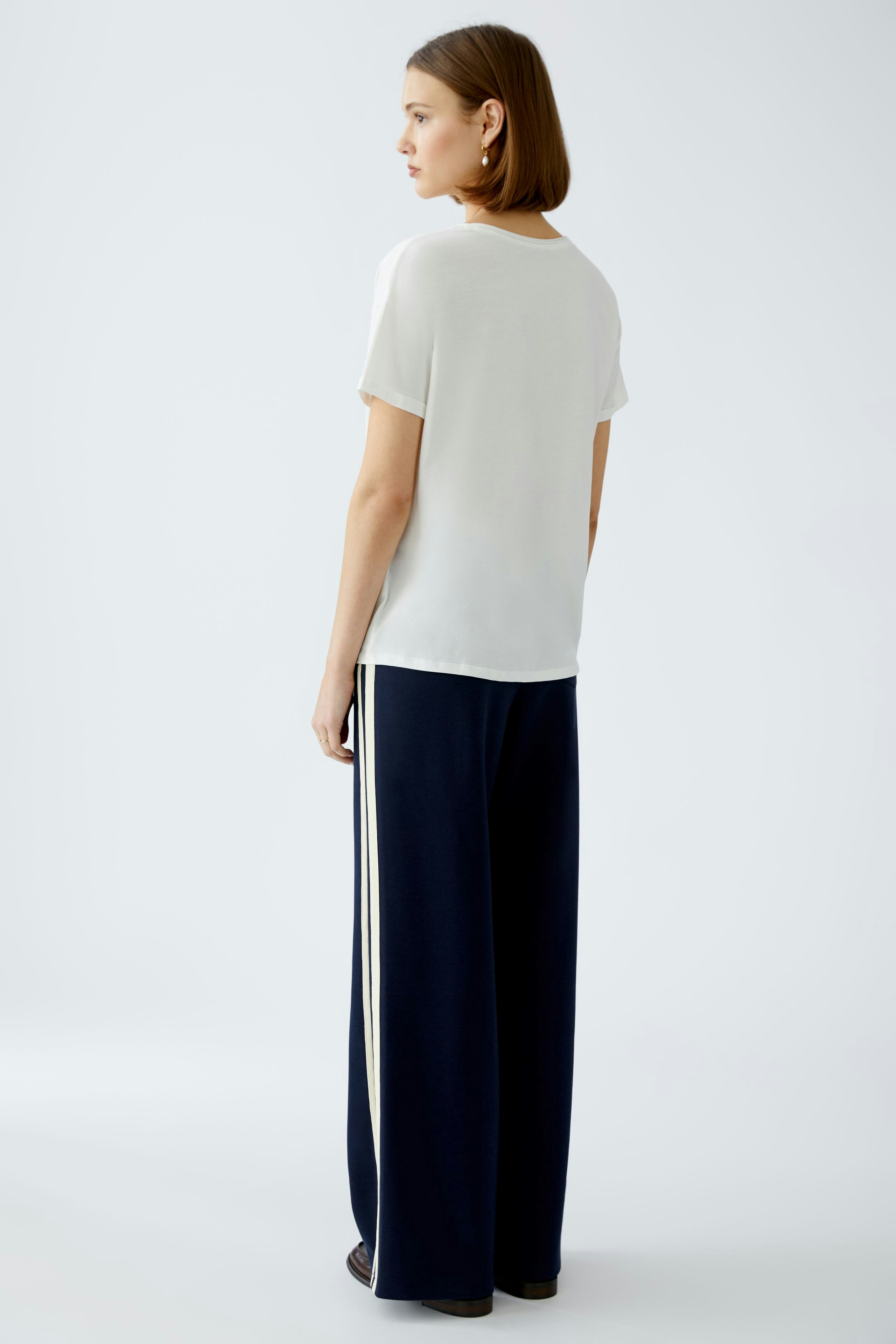 Elegant women's T-shirt: A woman in a white T-shirt paired with navy wide-leg pants.