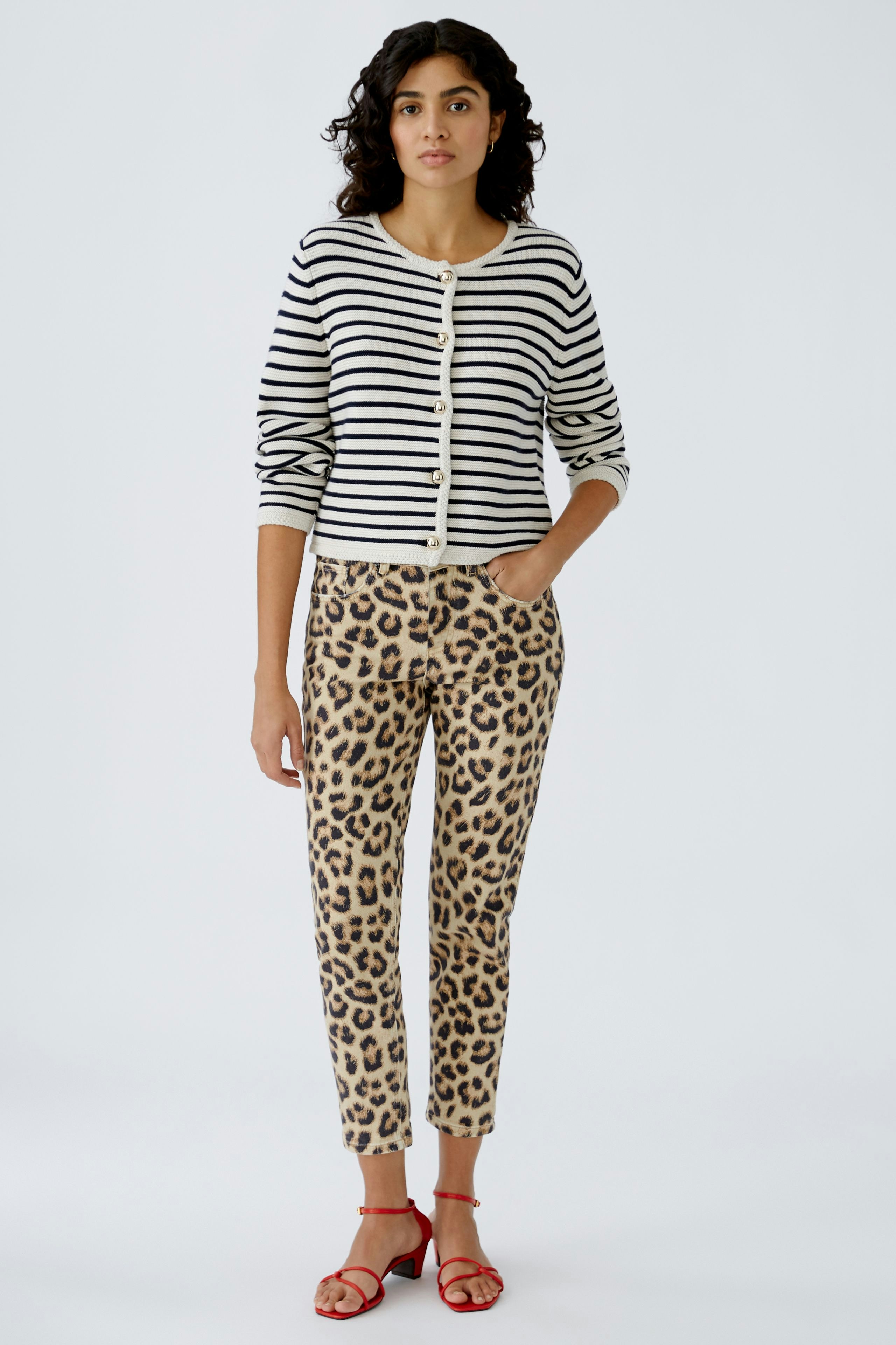 Damen Jeans Tapered: Frau in bequemen, gemusterten Jeans mit lässigem Oberteil und roten Sandalen.