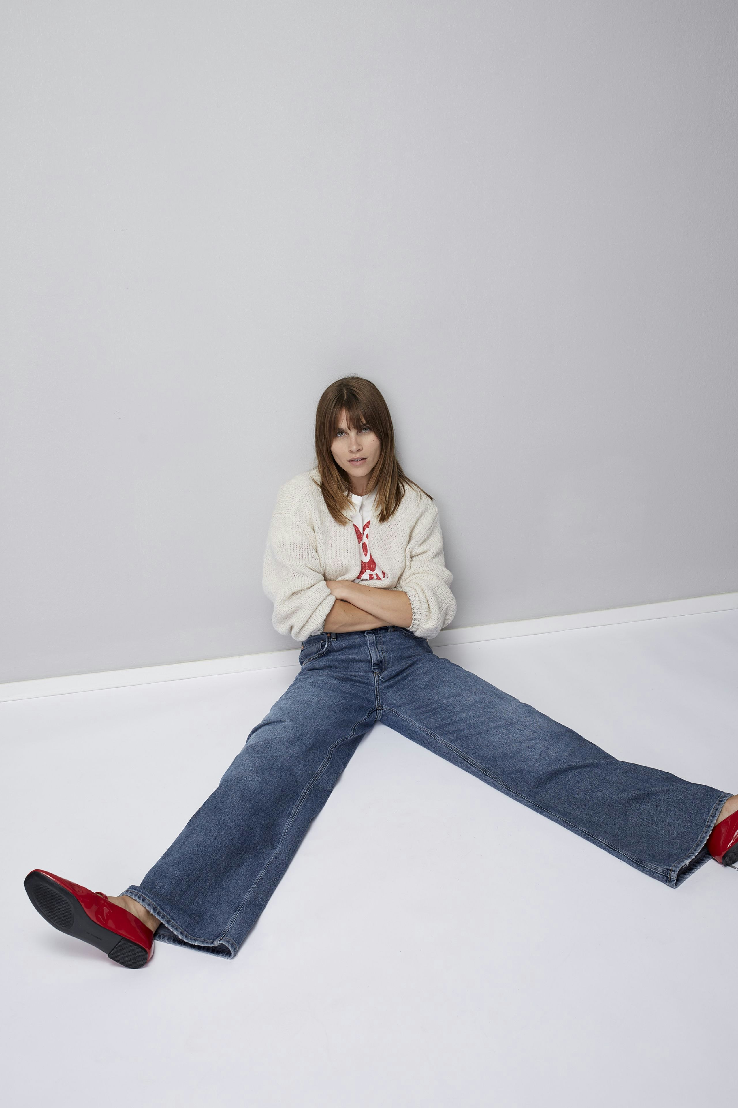 Stylish women's T-shirt: A woman in a cozy white pullover with a playful design, exuding casual elegance.