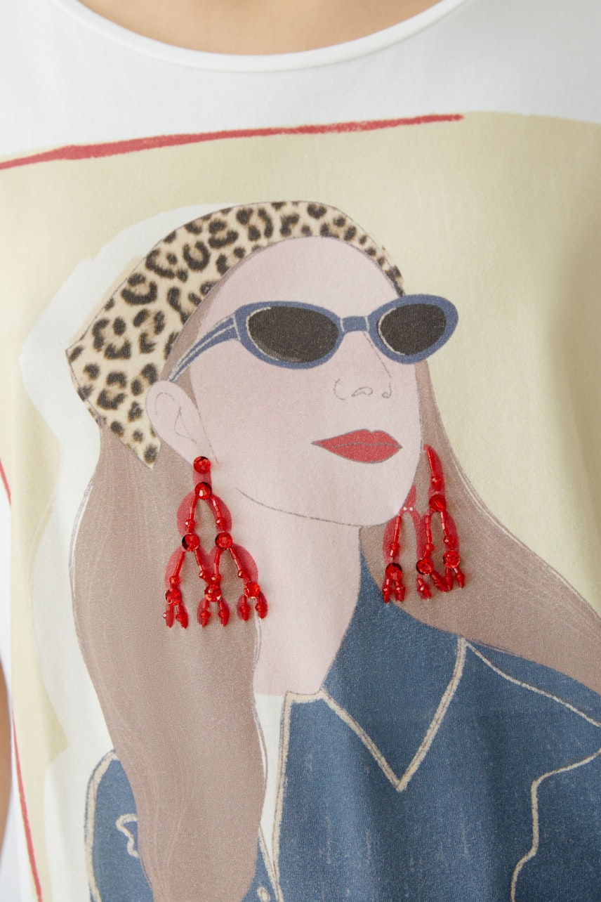 Stylish women's T-shirt featuring a graphic print of a woman with sunglasses and bold earrings.