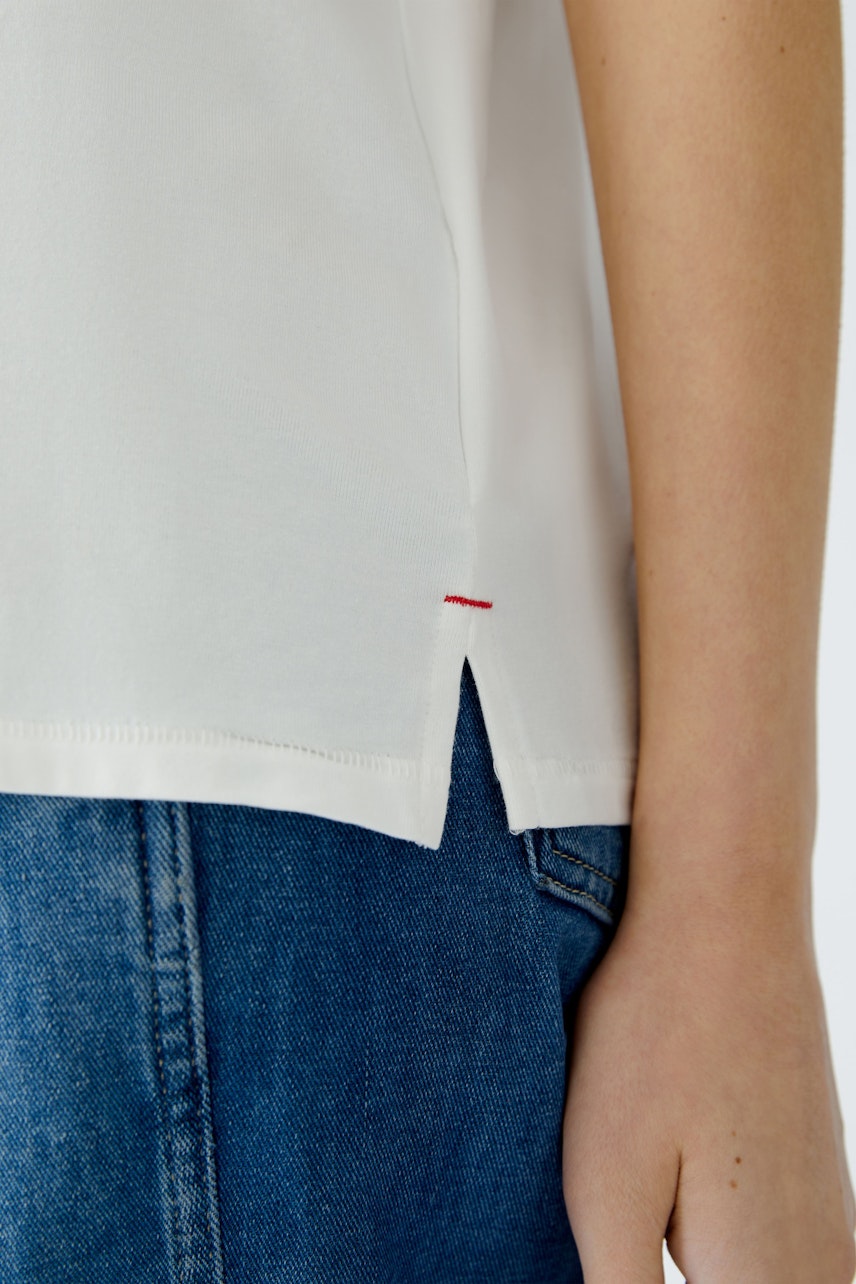 Stylish women's T-shirt: Close-up of a woman wearing a white T-shirt with a subtle red detail.