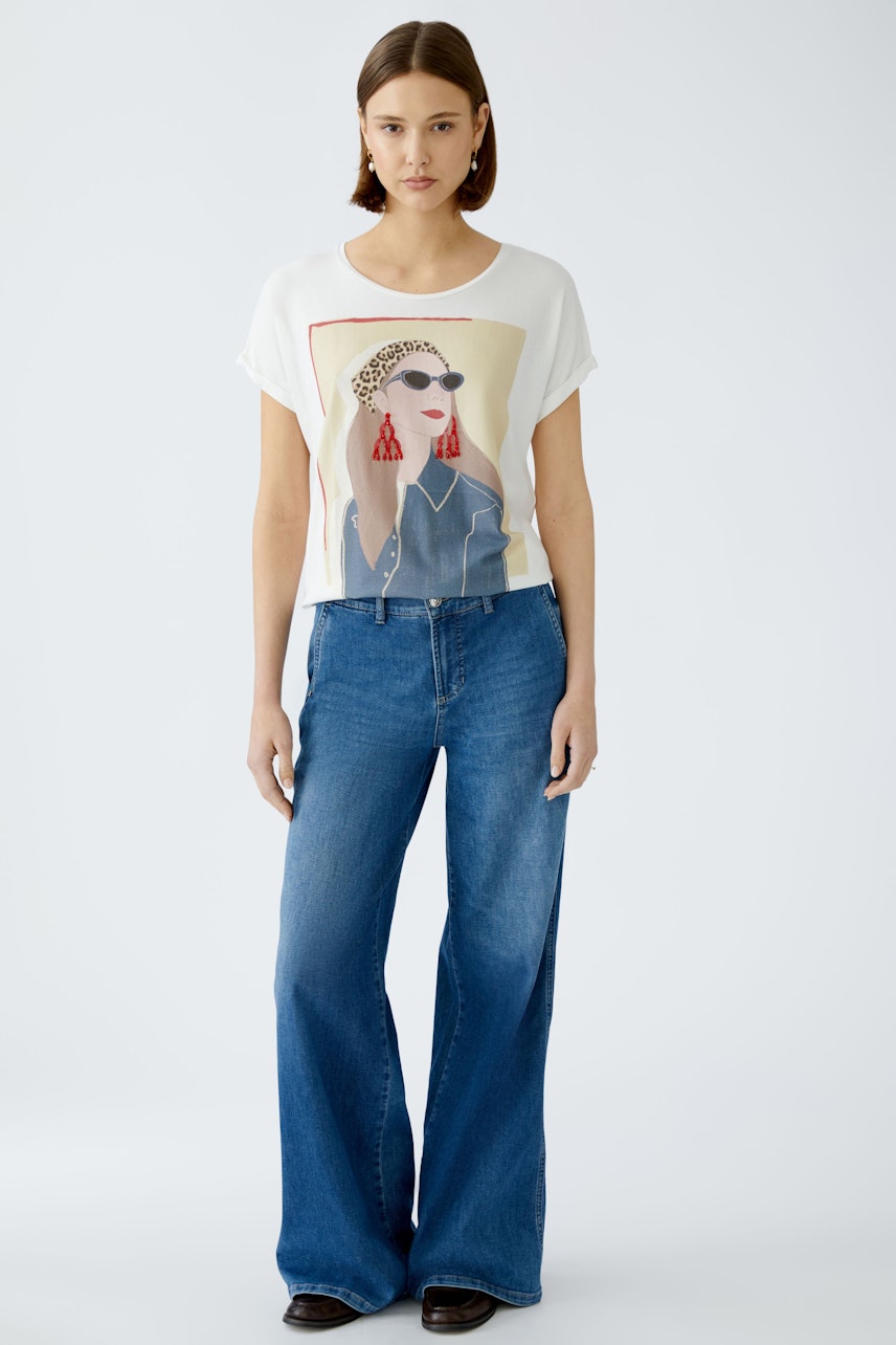 Stylish women's T-shirt featuring a graphic print, paired with flared jeans for a chic look.