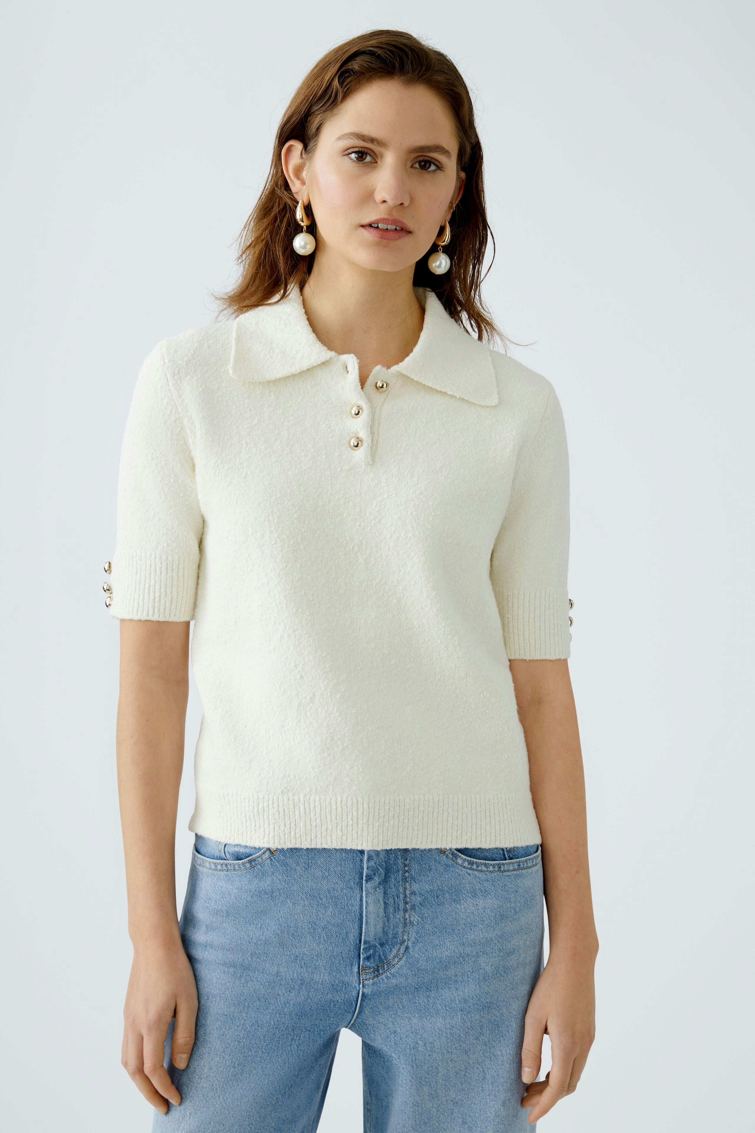 Stylish women's pullover: A woman in a cream short-sleeve pullover with a collar and button details.