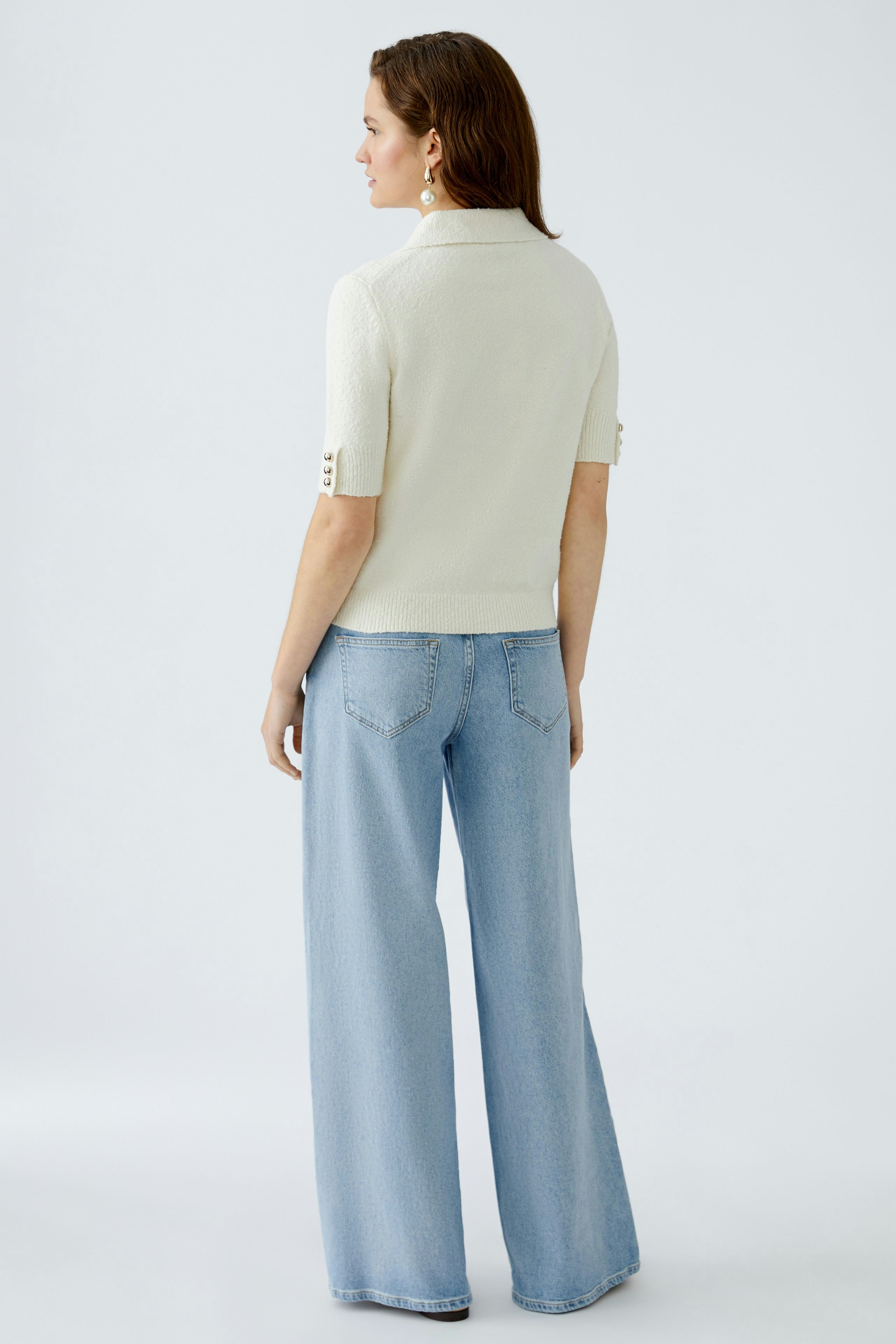 Stylish women's pullover: A woman in a cream short-sleeve pullover paired with wide-leg jeans.