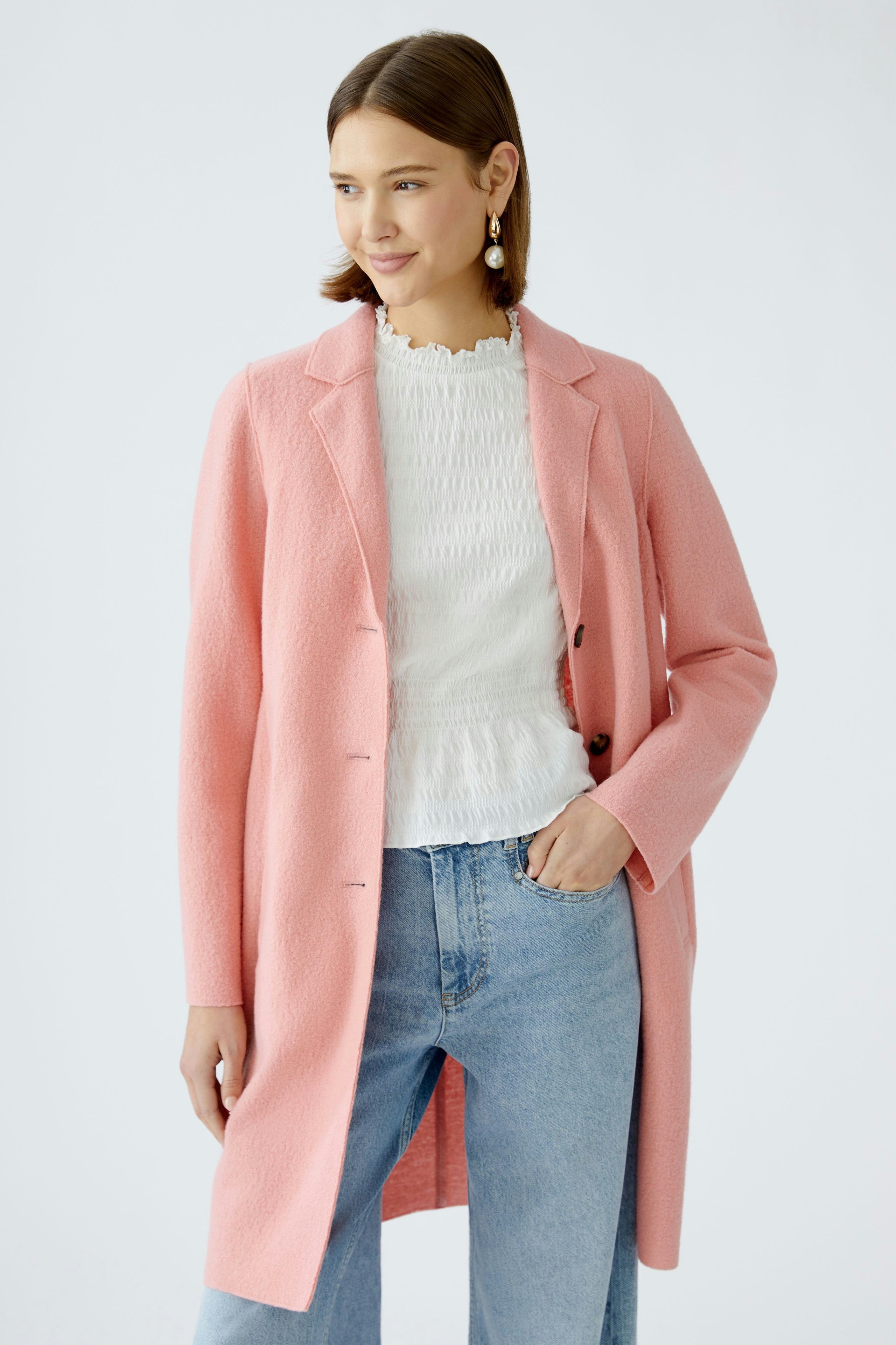 Stylish women's coat: A woman in a pink coat over a white top and jeans, exuding elegance.