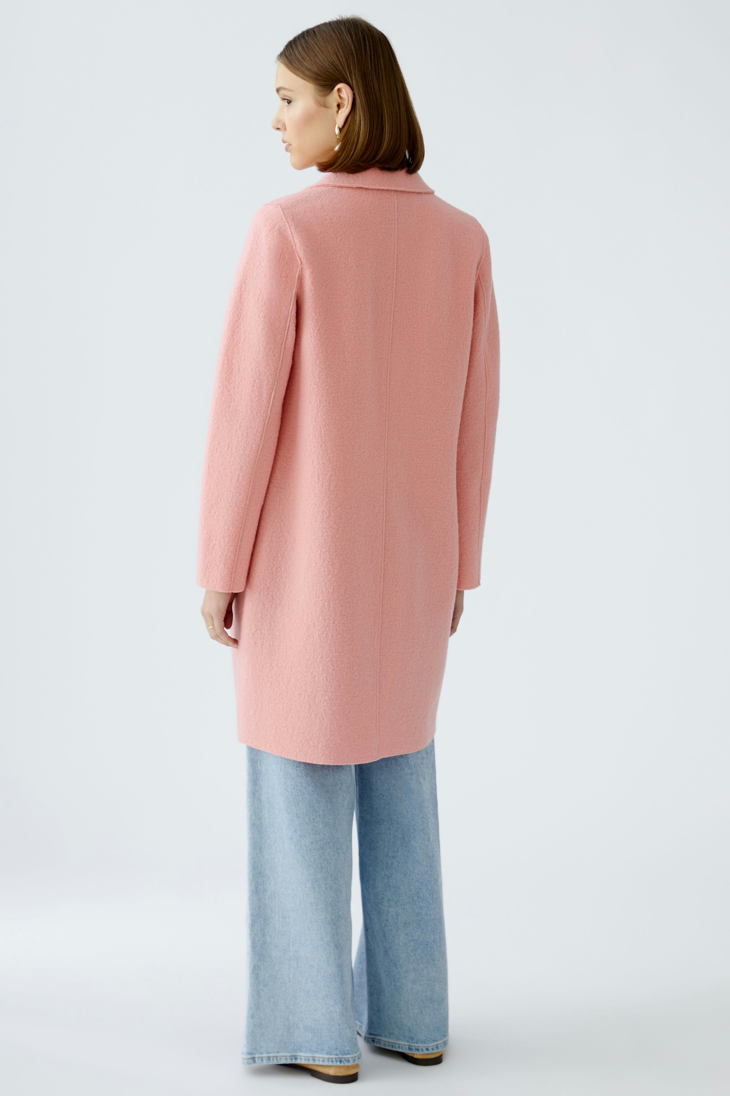 Stylish women's coat: A woman in a pink coat with a relaxed fit, paired with wide-leg jeans.