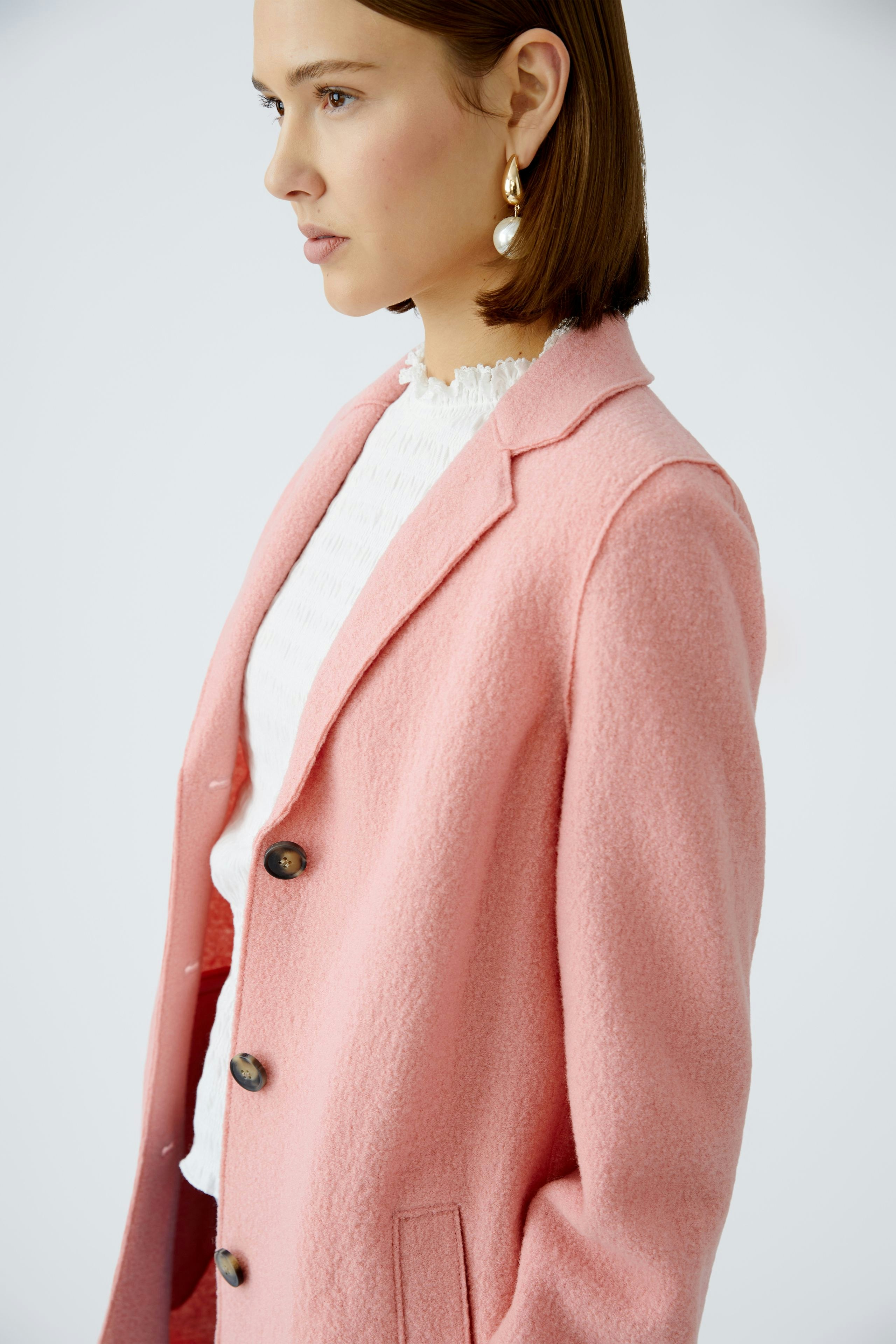 Stylish women's coat: A woman in a soft pink coat with buttons, exuding elegance and warmth.
