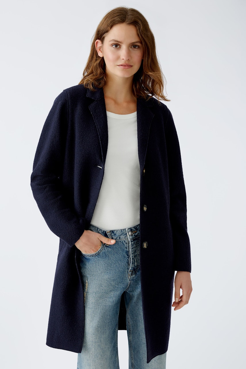 Stylish women's wool coat: A woman in a navy coat over a white top and jeans, exuding elegance.