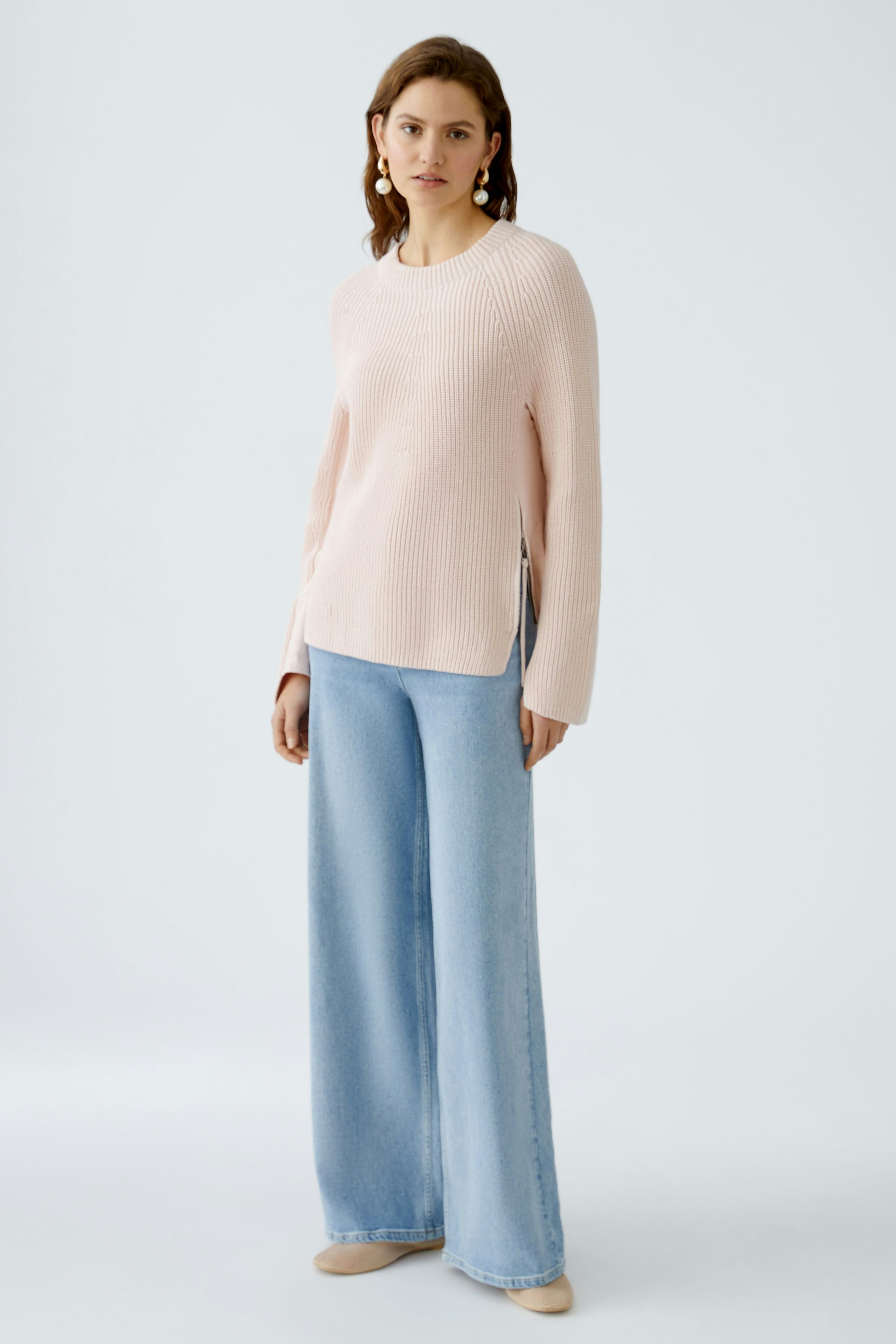 Damen-Pullover: Frau in zartem rosa Strickpullover mit lässigem Schnitt und seitlichen Schlitzen.