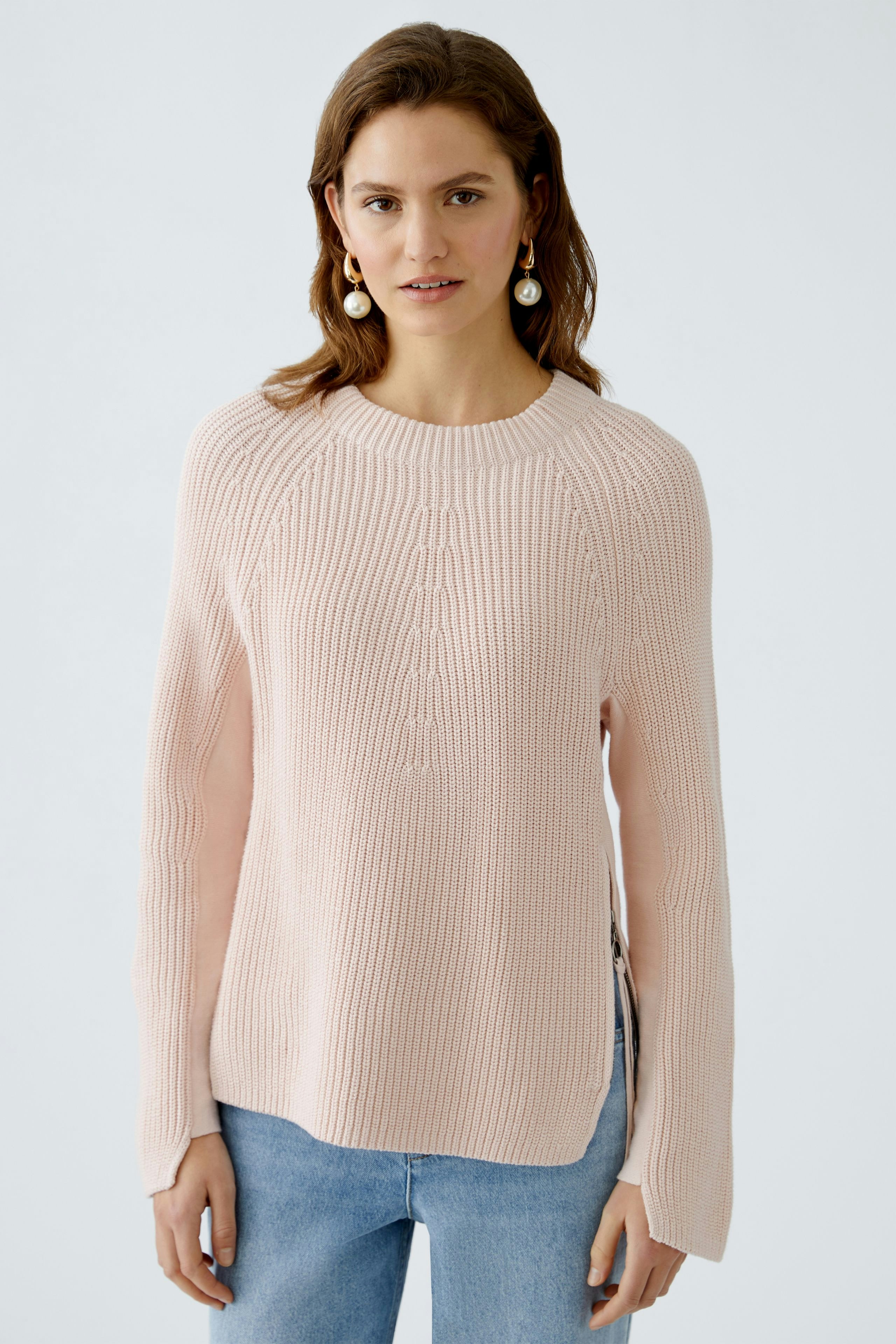 Damen-Pullover: Frau trägt einen hellrosa Strickpullover mit lässigem Schnitt und langen Ärmeln.