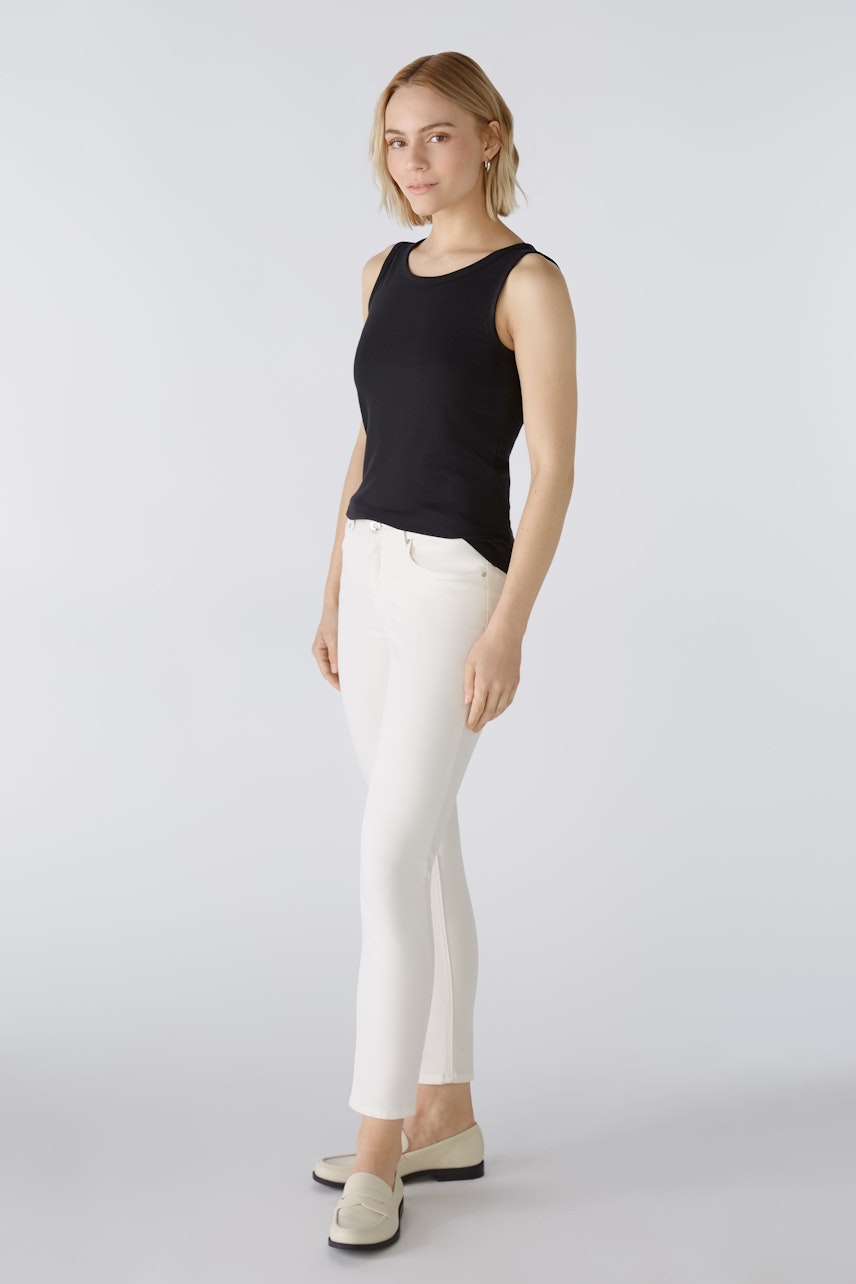 Stylish jeggings: A woman in white jeggings paired with a black tank top, showcasing a modern look.