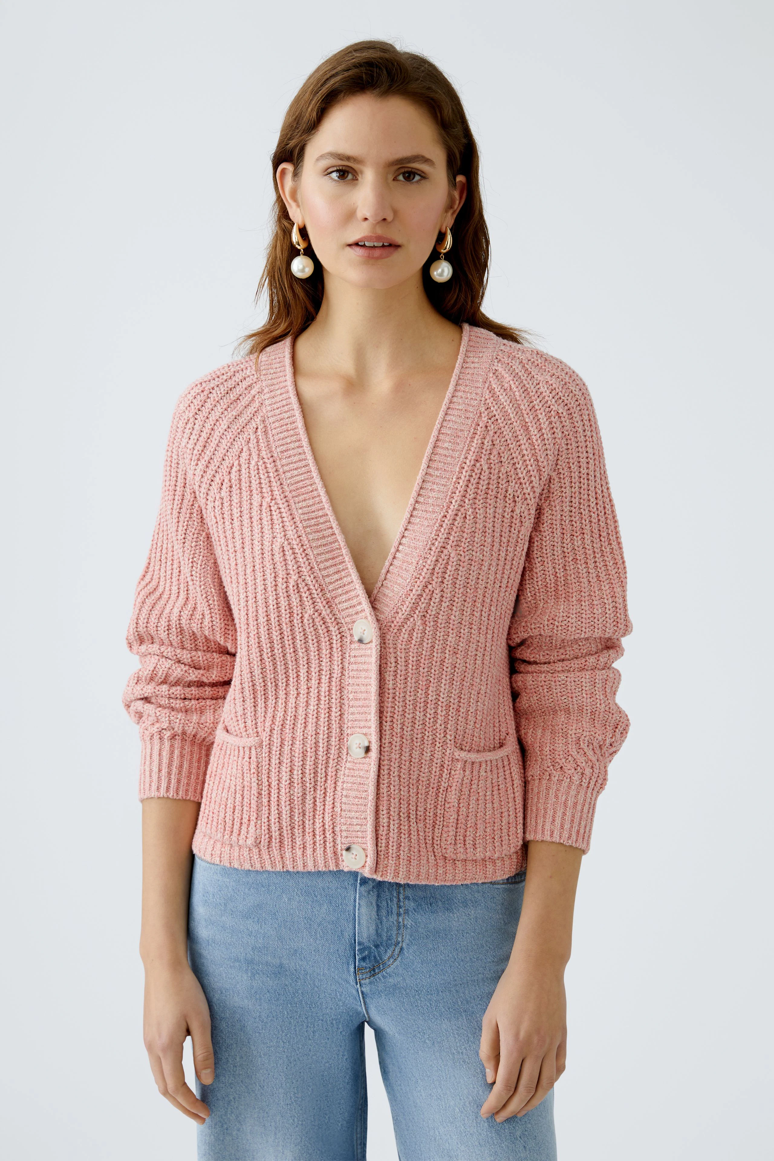 Stylish women's cardigan: A woman in a pink knitted cardigan with buttons and pockets, exuding casual elegance.