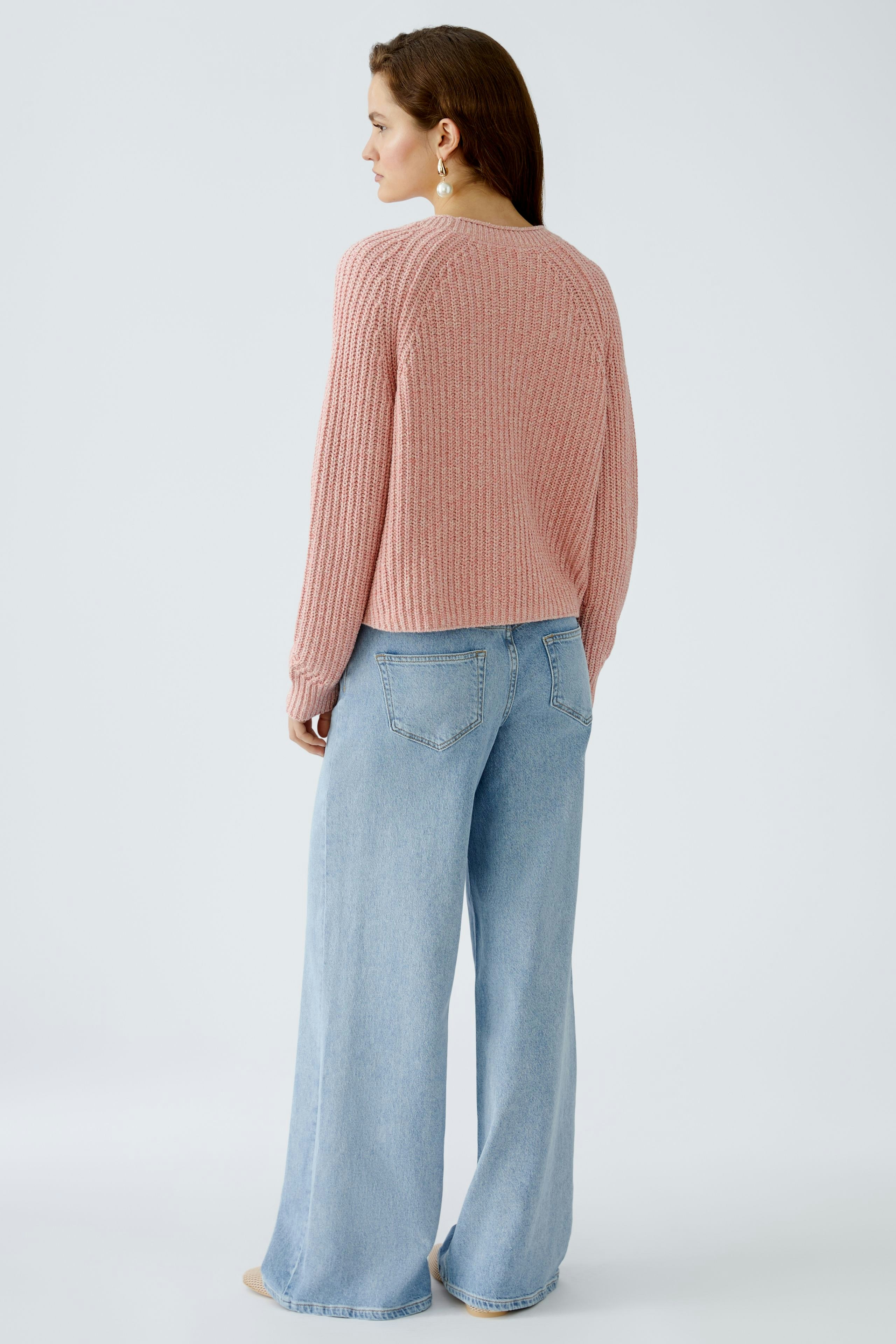 Stylish women's cardigan: A woman in a pink ribbed cardigan paired with wide-leg jeans.