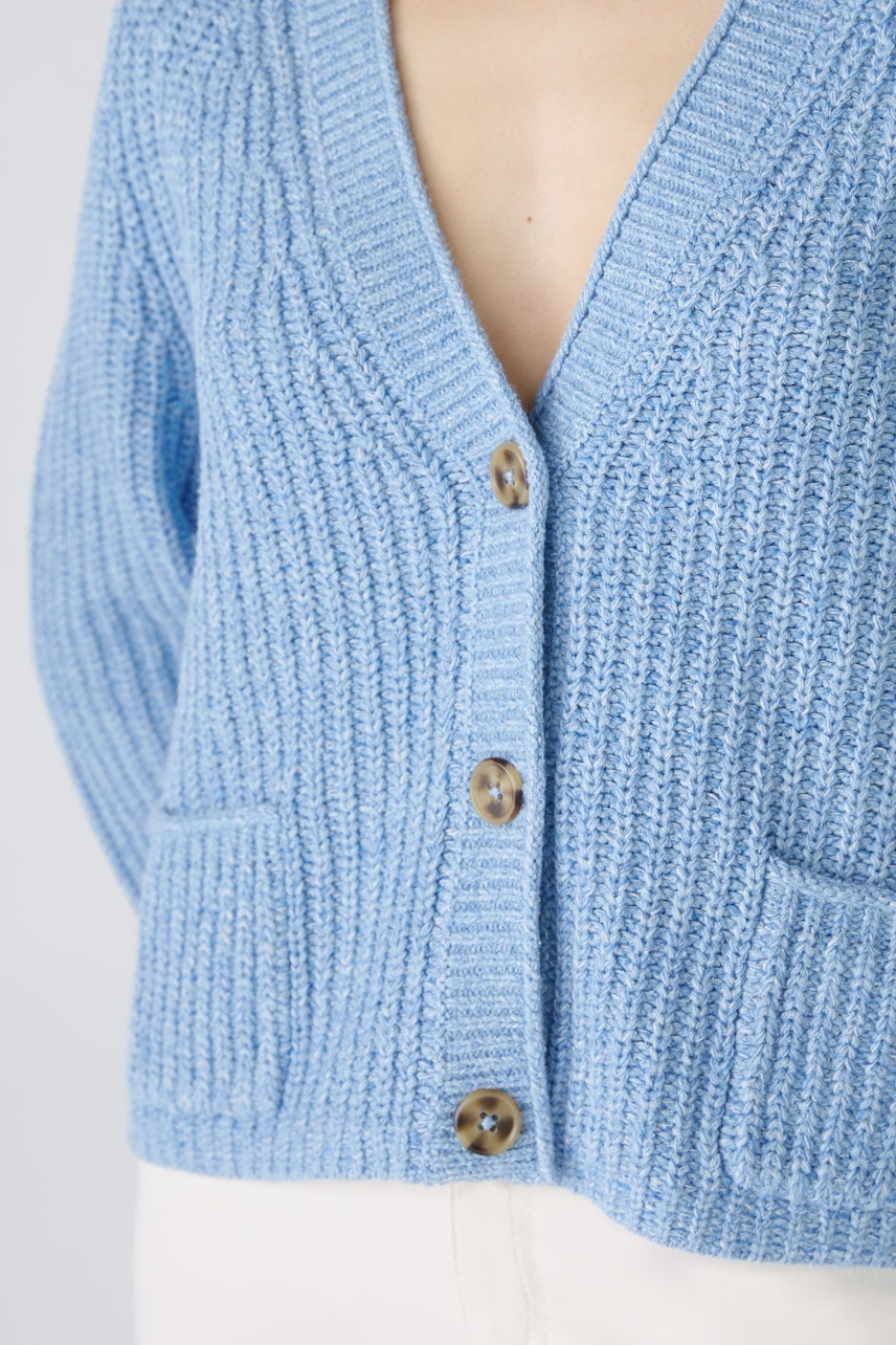 Stylish women's cardigan in soft blue with a V-neck and button closure, featuring two front pockets.