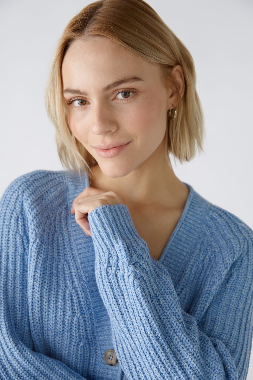 Stylish women's cardigan: A woman in a light blue knitted cardigan with a relaxed fit and button details.