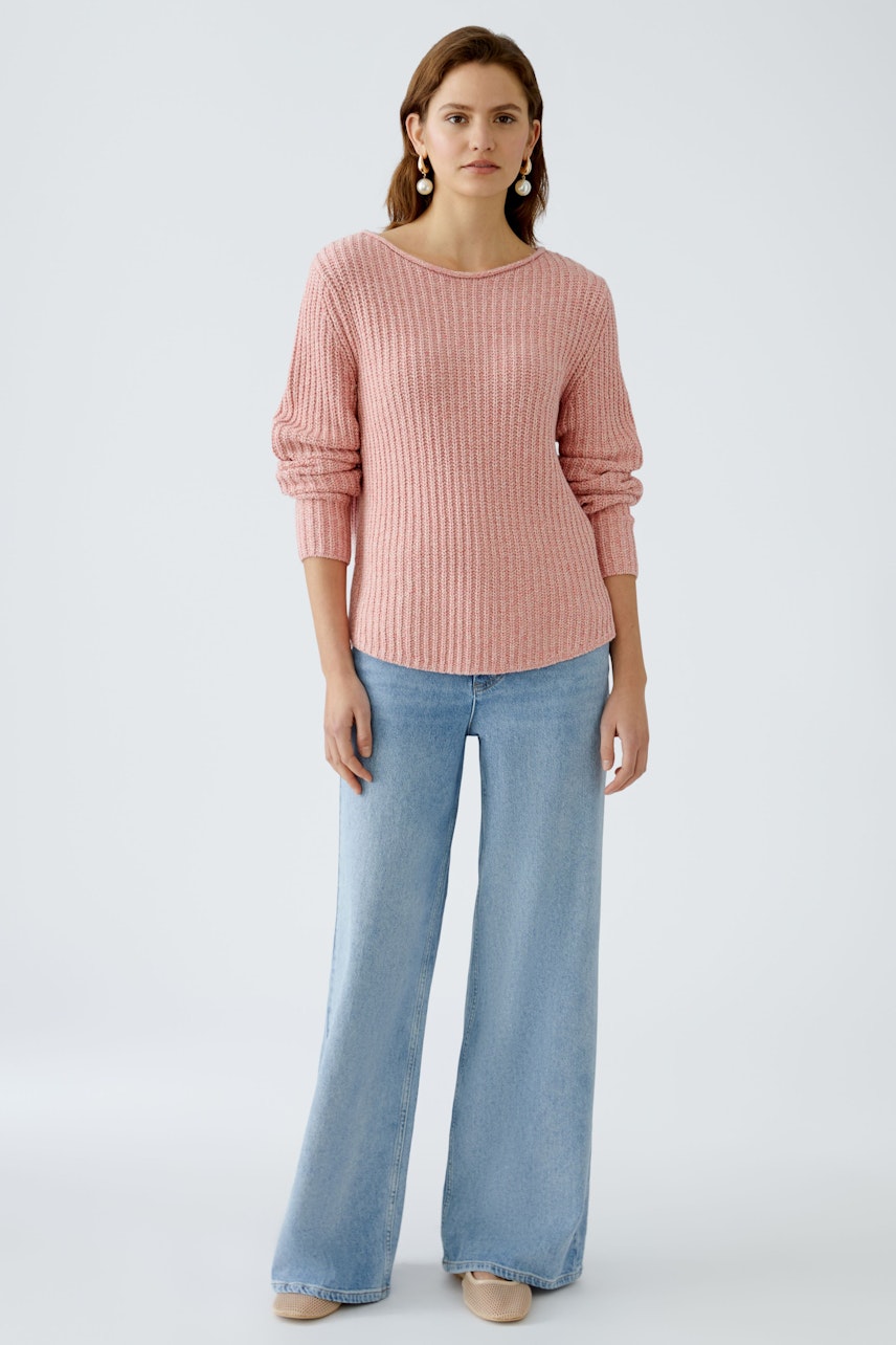 Damen-Pullover: Frau in rosa, geripptem Pullover mit lässigem Schnitt und weiten Jeans.