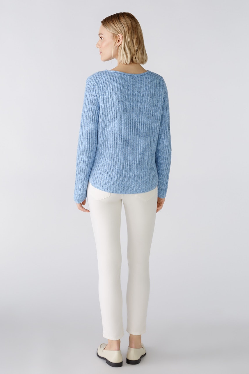 Stylish women's pullover: A woman in a light blue ribbed pullover paired with white pants.