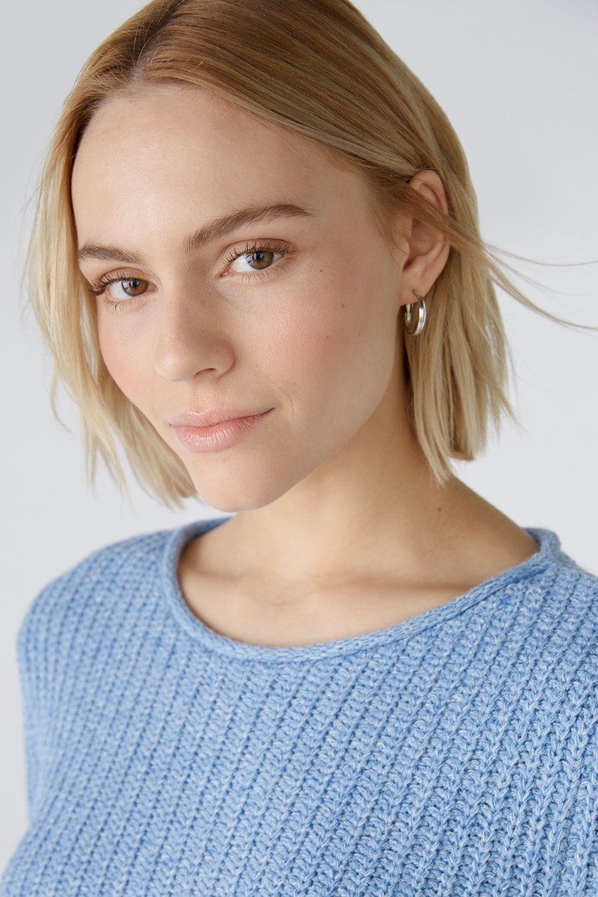 Modern women's pullover: A woman in a light blue textured pullover with a relaxed fit.