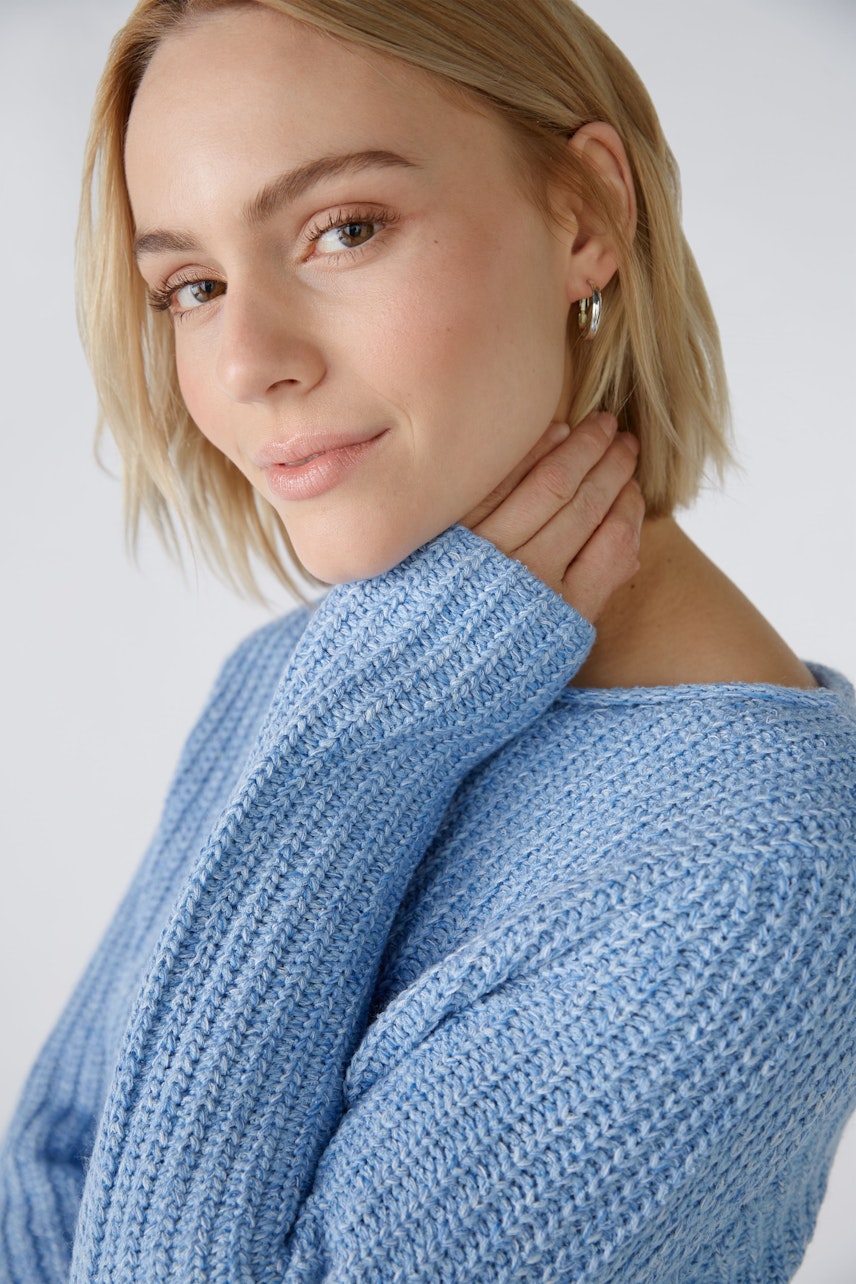 Modern women's pullover: A woman in a light blue knitted pullover with long sleeves, smiling softly.