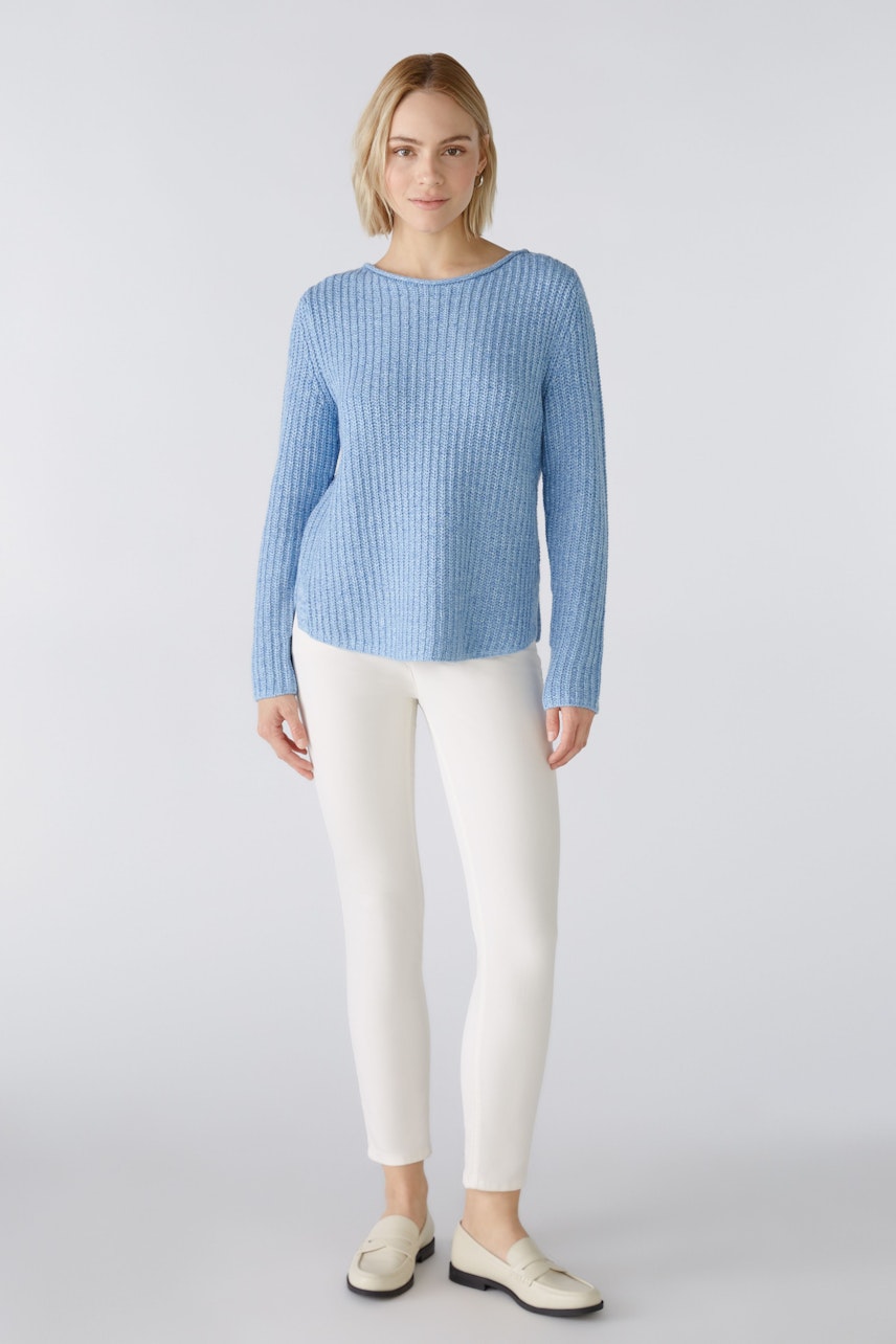 Modern women's pullover: A woman in a light blue ribbed pullover paired with white pants.