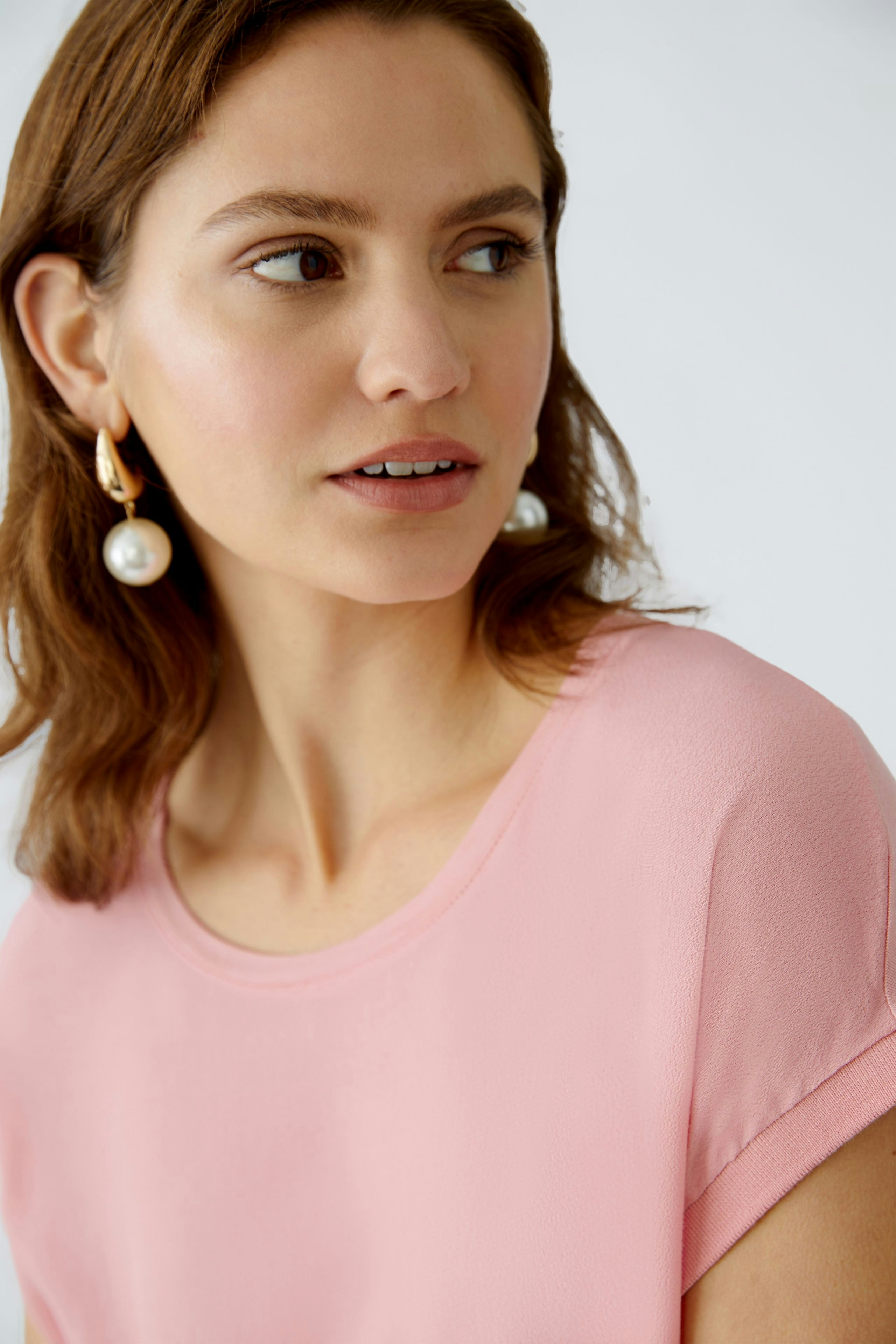 Elegantes Blusenshirt: Frau trägt ein zartrosa Blusenshirt mit lässigem Schnitt und dezenten Details.