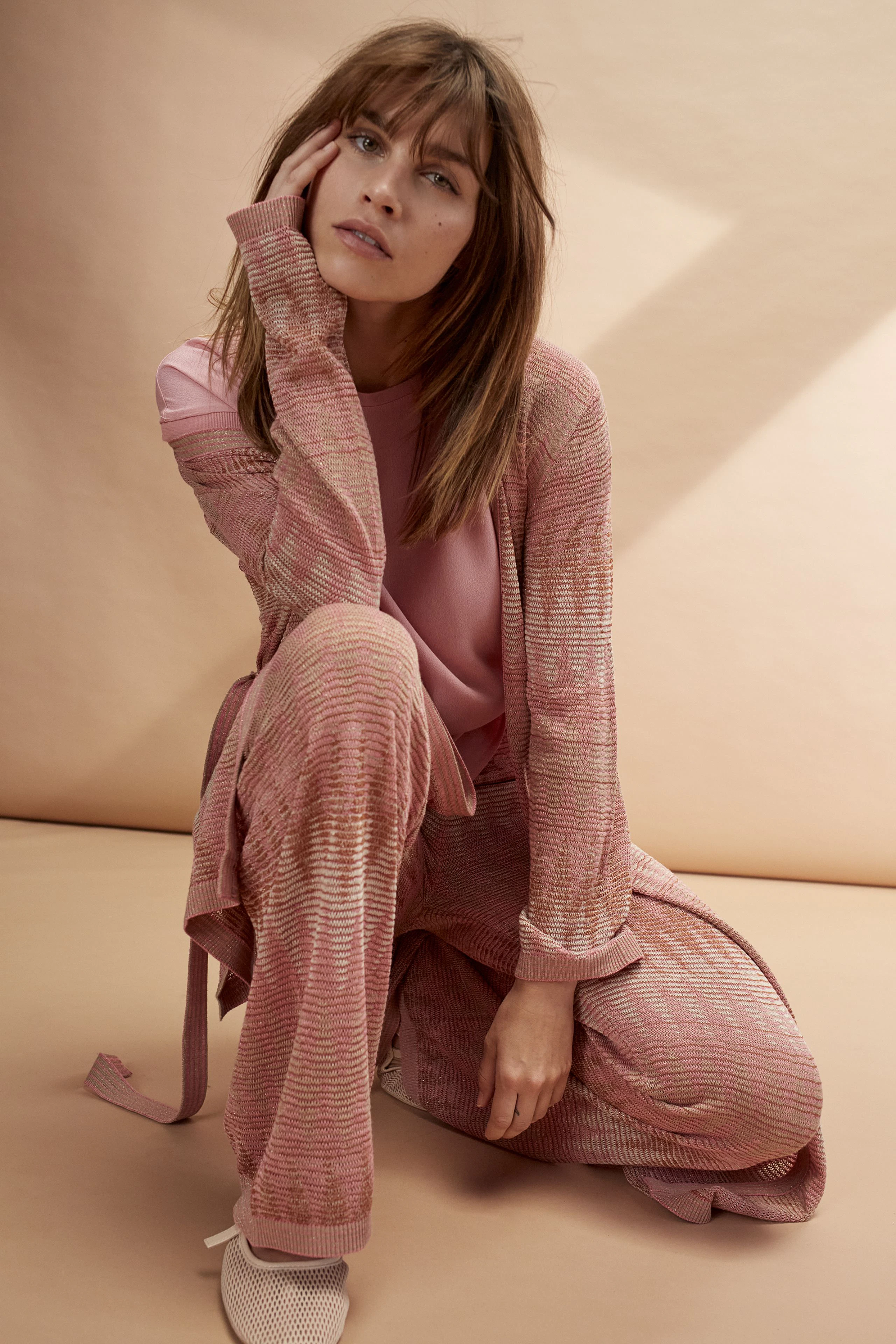 Stylish women's blouse shirt: A woman in a pink striped blouse shirt and matching pants poses elegantly.