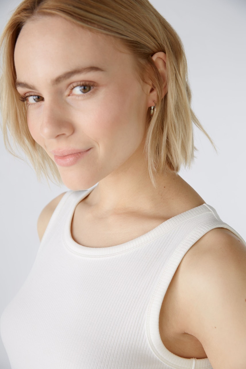 Stylish women's top: A woman in a white ribbed tank top, showcasing a modern and casual look.