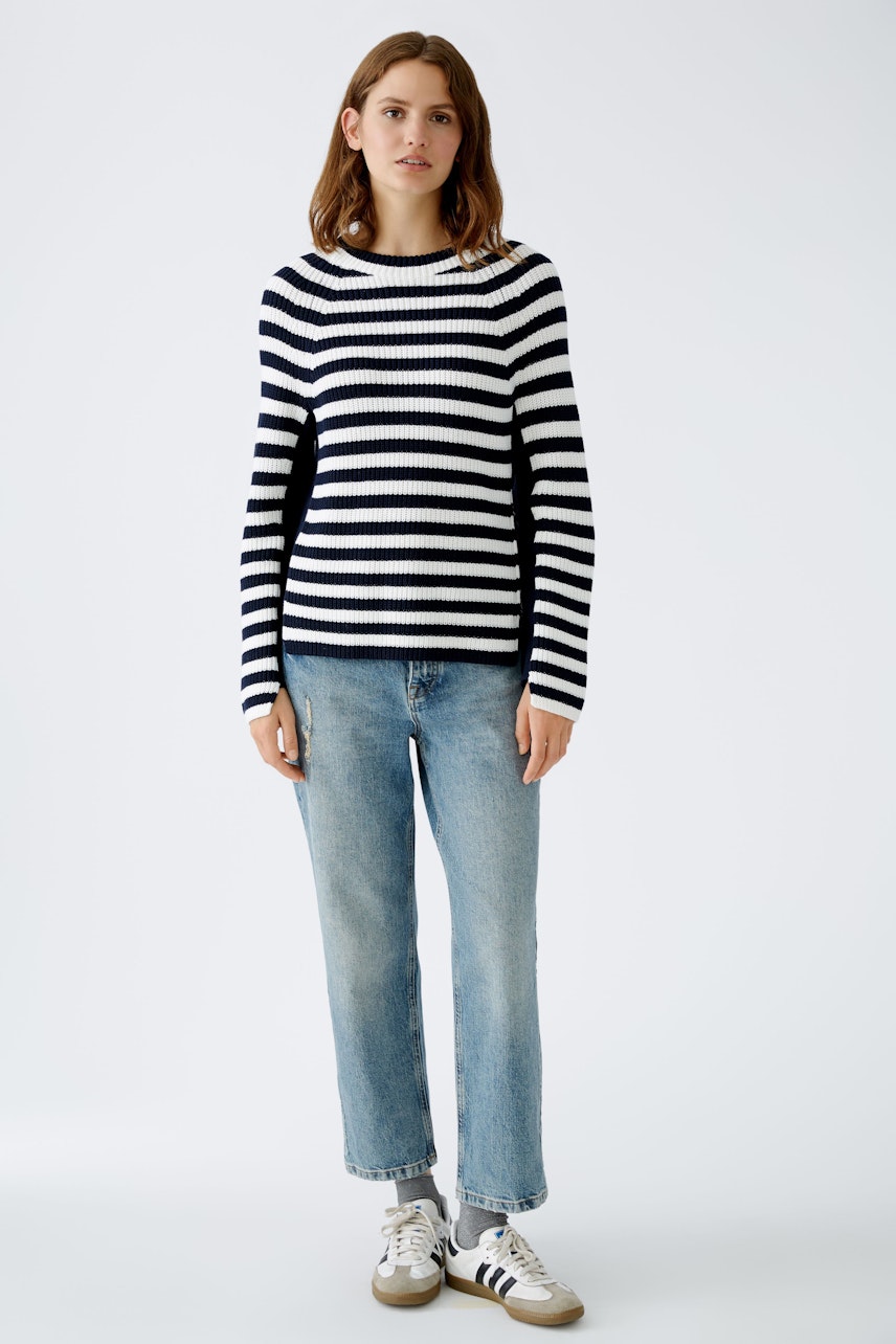 Stylish women's pullover: A woman in a navy and white striped pullover paired with light jeans.