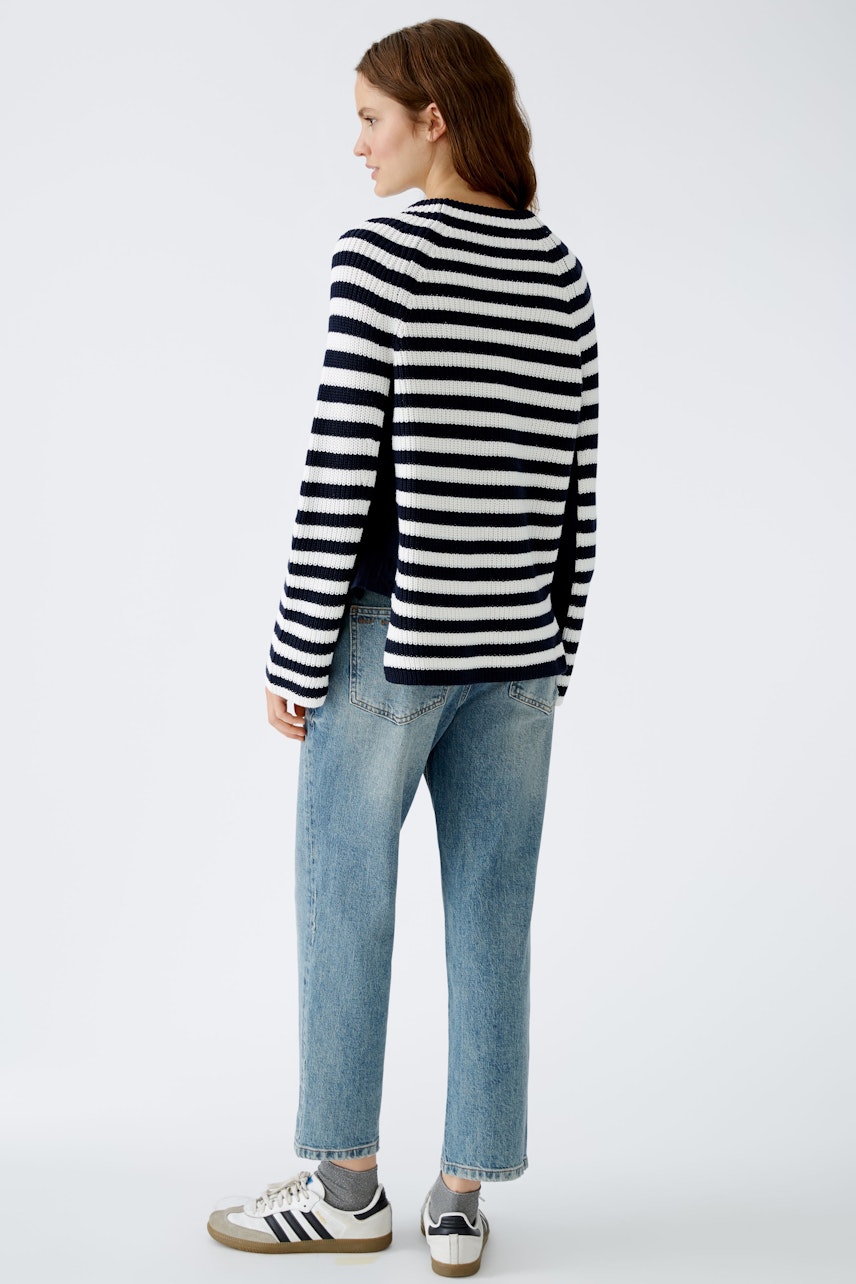 Stylish women's pullover: A woman in a striped pullover and relaxed jeans stands confidently.