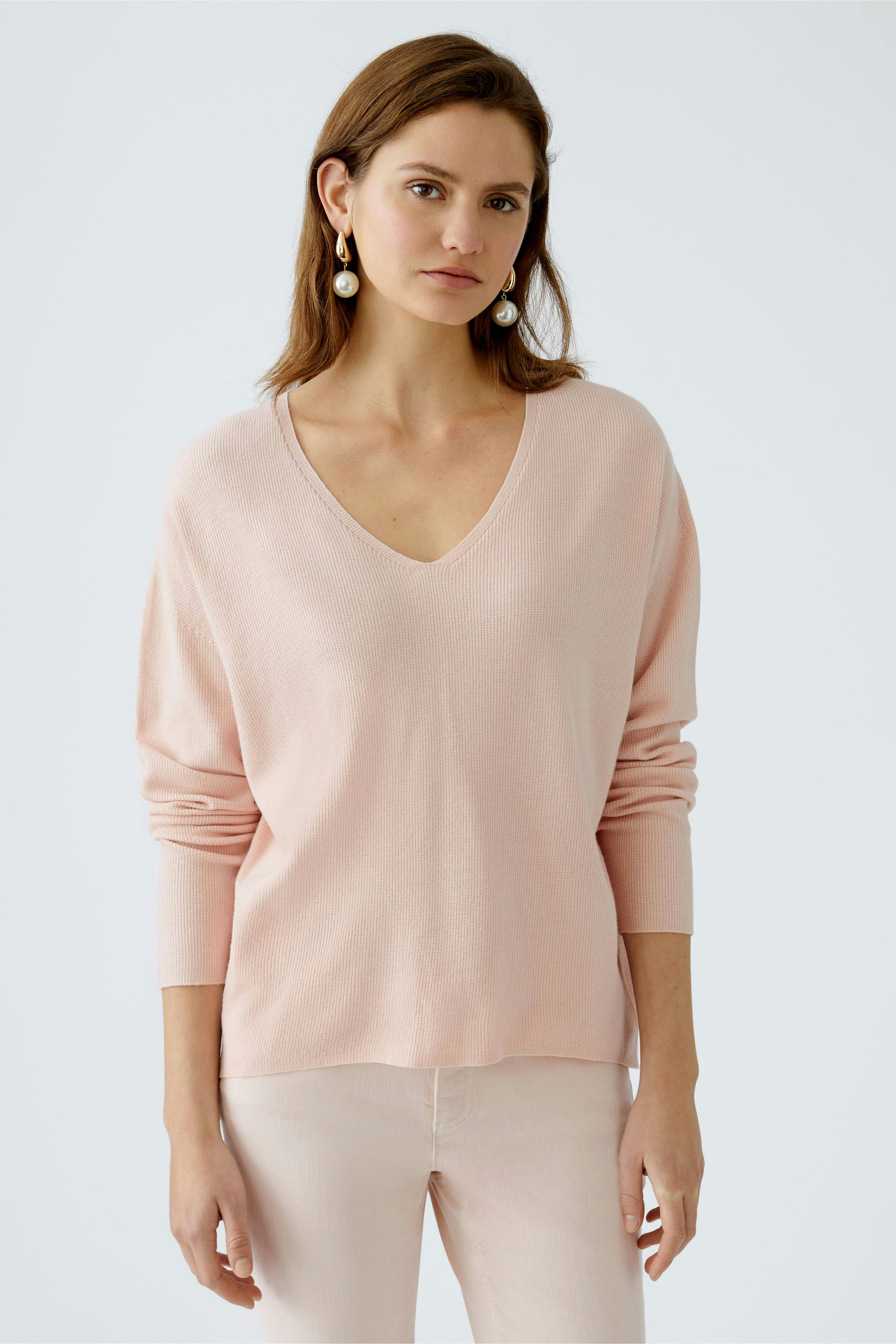 Stylish women's pullover: A woman in a soft pink V-neck pullover, exuding elegance and comfort.
