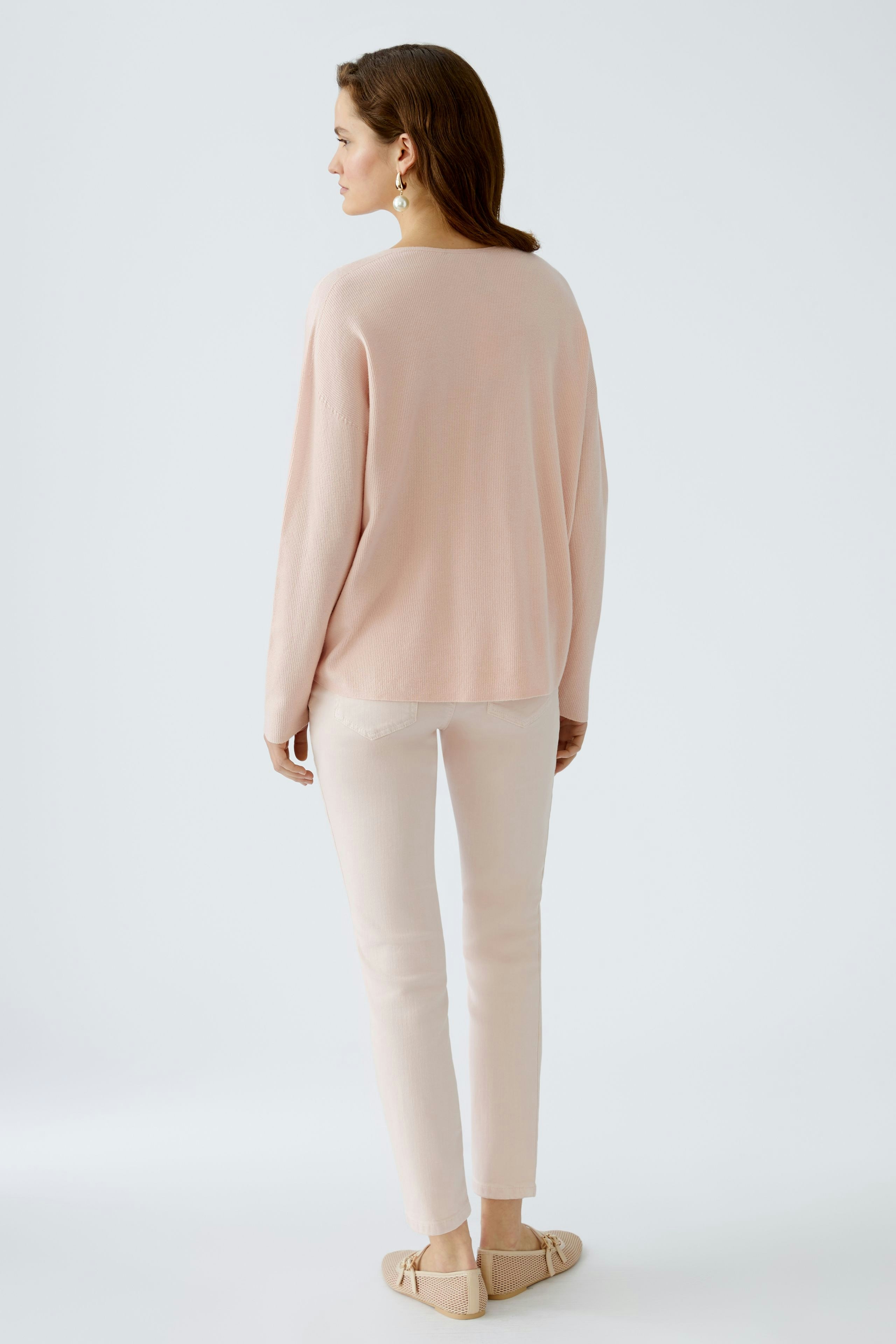 Stylish women's pullover in soft pink, worn with light pants, showcasing a relaxed fit.