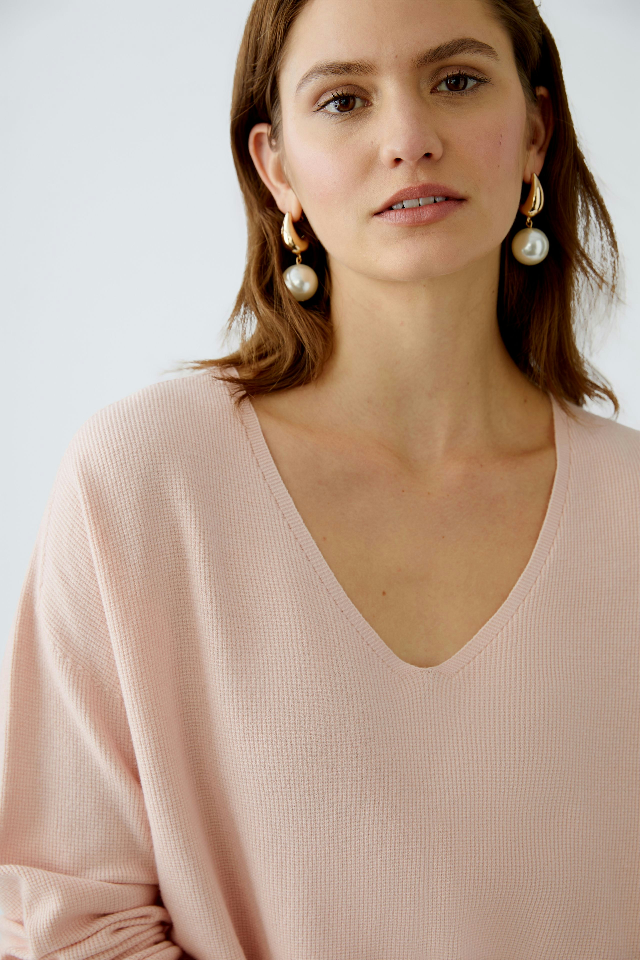 Stylish women's pullover in soft pink with a deep V-neck, perfect for casual or chic outfits.