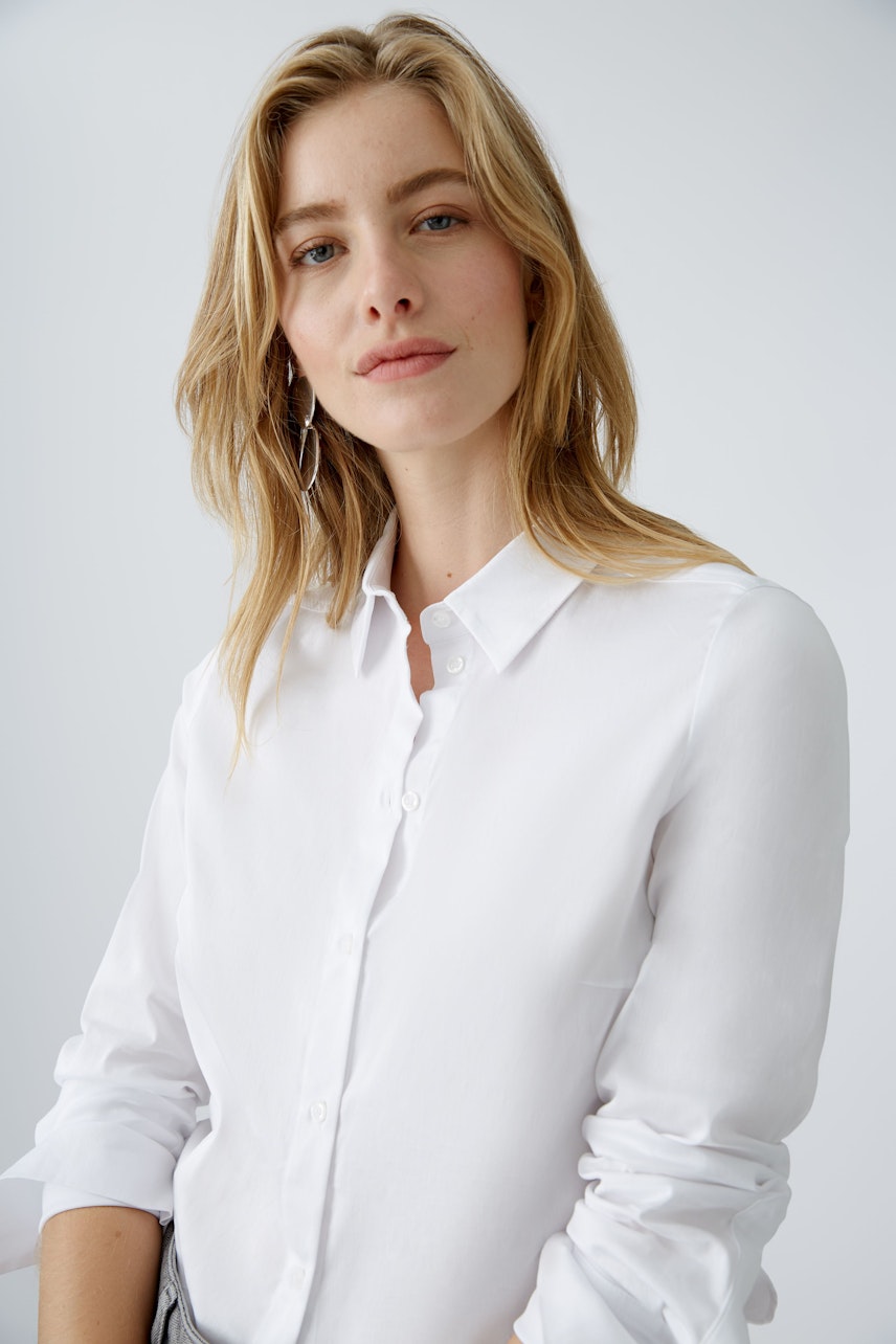 Elegante Damen-Bluse: Frau in weißer Bluse mit klassischem Kragen und lässigem Look.