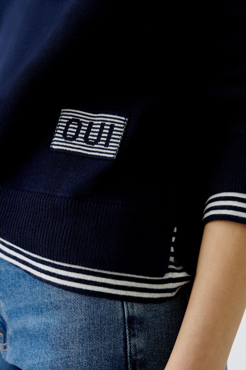 Stylish women's pullover: Close-up of a navy pullover with striped details and logo.