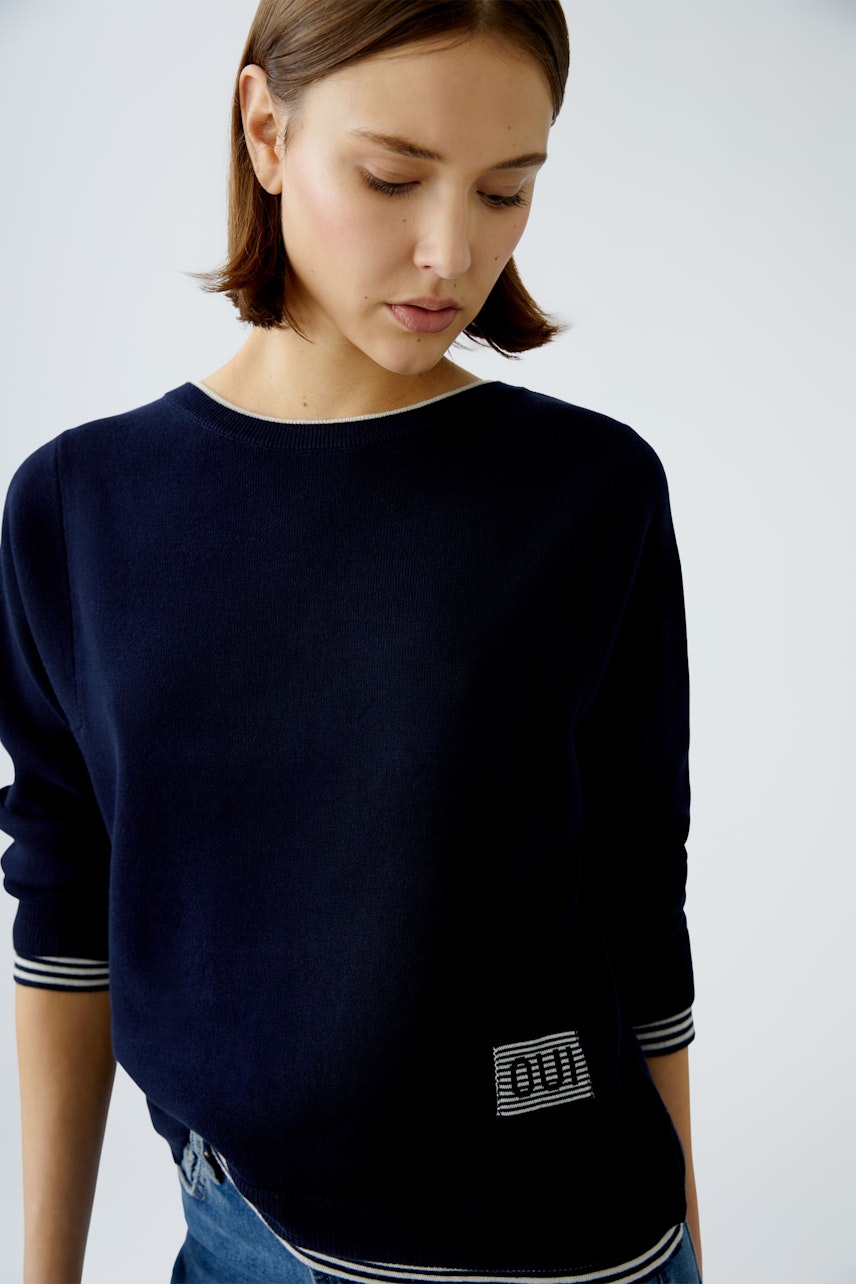 Modern women's pullover: A woman in a navy pullover with striped cuffs, exuding casual elegance.