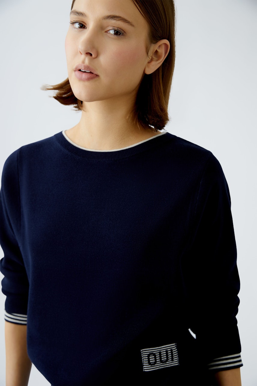 Modern women's pullover: A woman in a navy pullover with striped details, exuding casual elegance.