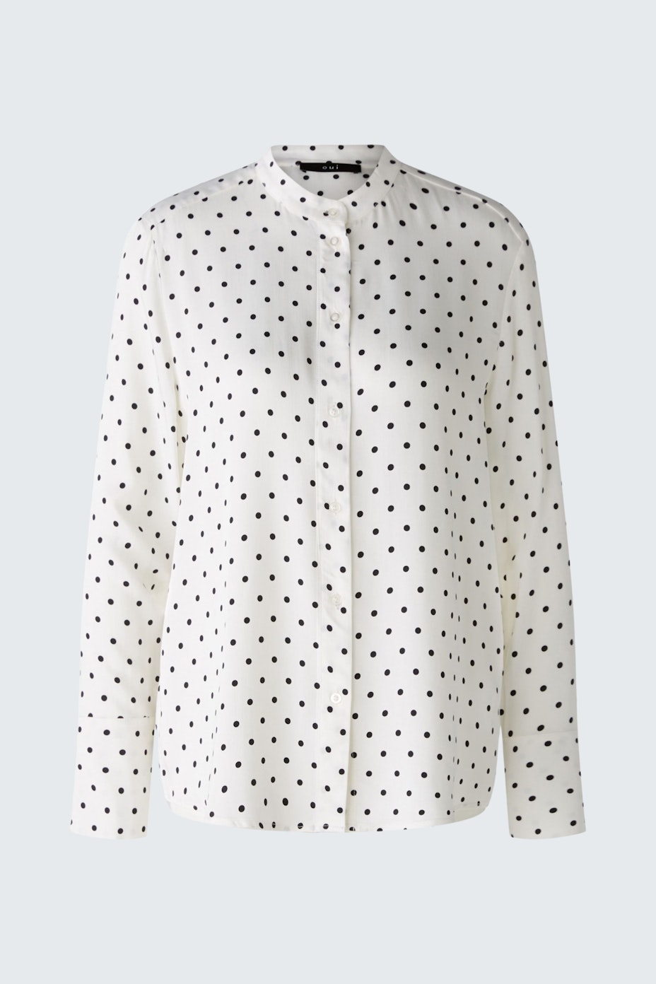 Chic women's shirt: A woman in a white shirt with black polka dots, perfect for casual or formal occasions.