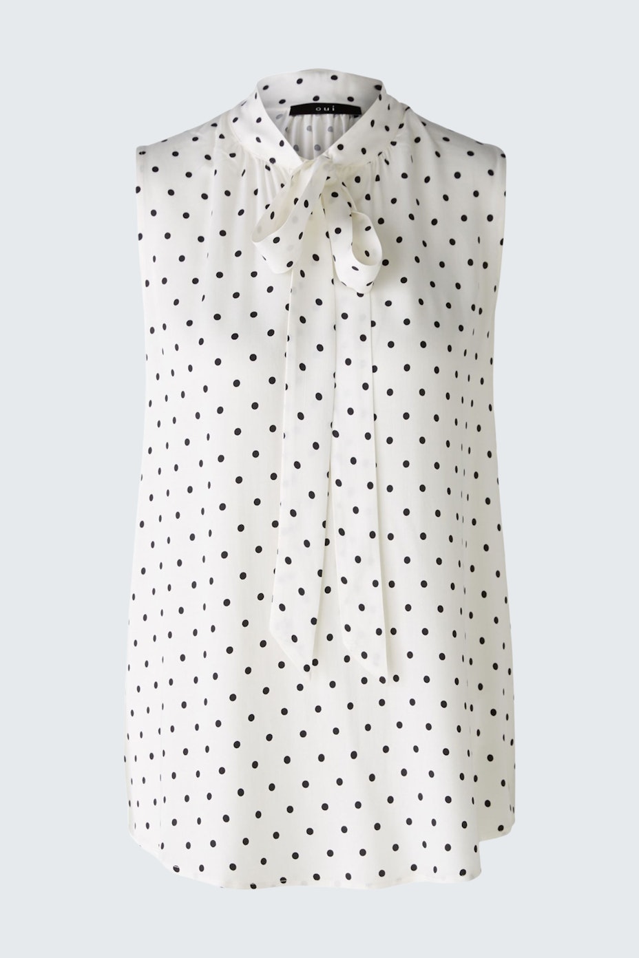 Elegant sleeveless blouse: A stylish white top with black polka dots and a bow tie detail.