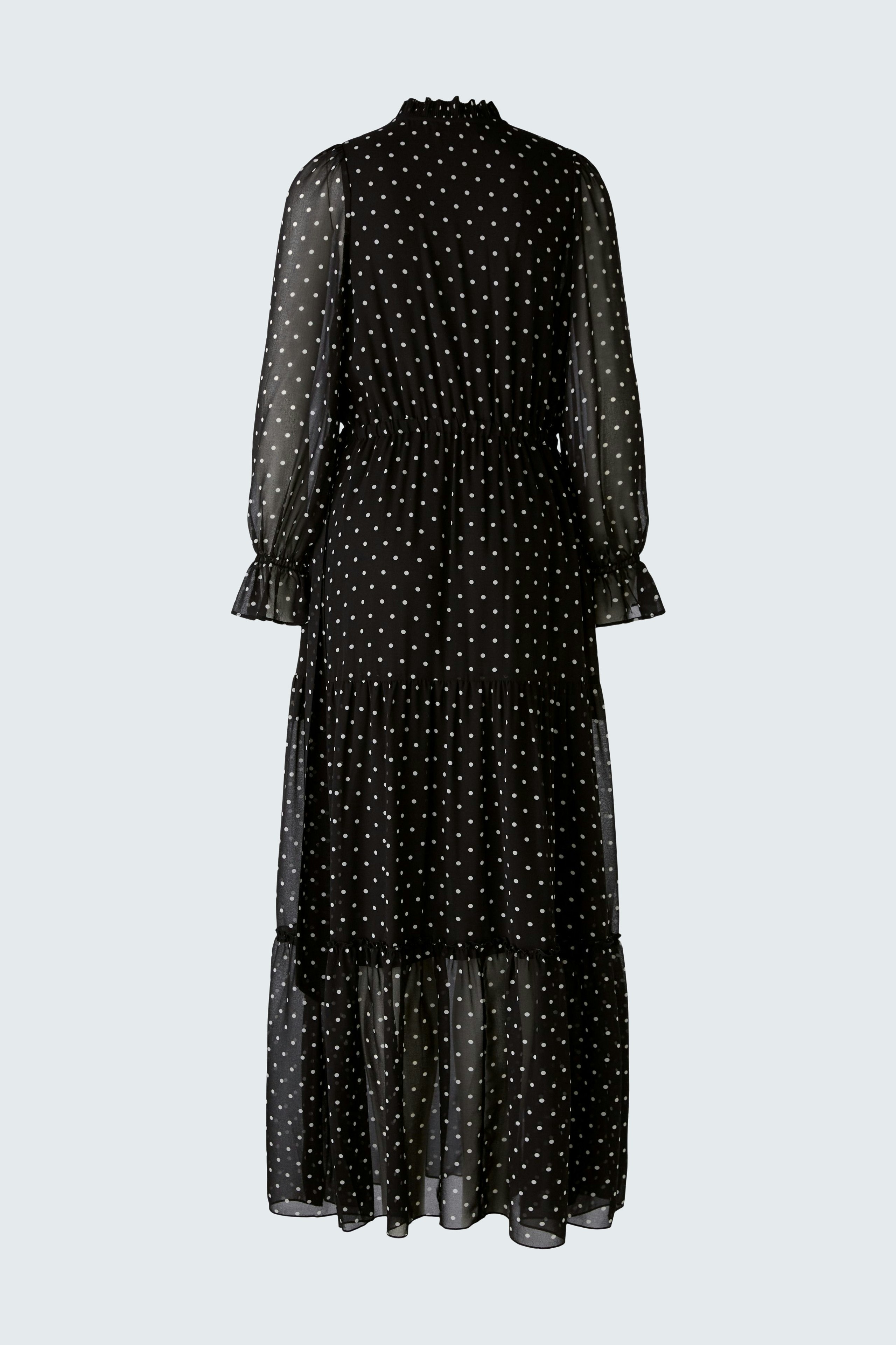 Elegant evening dress: A woman in a long black dress with white polka dots and sheer sleeves.
