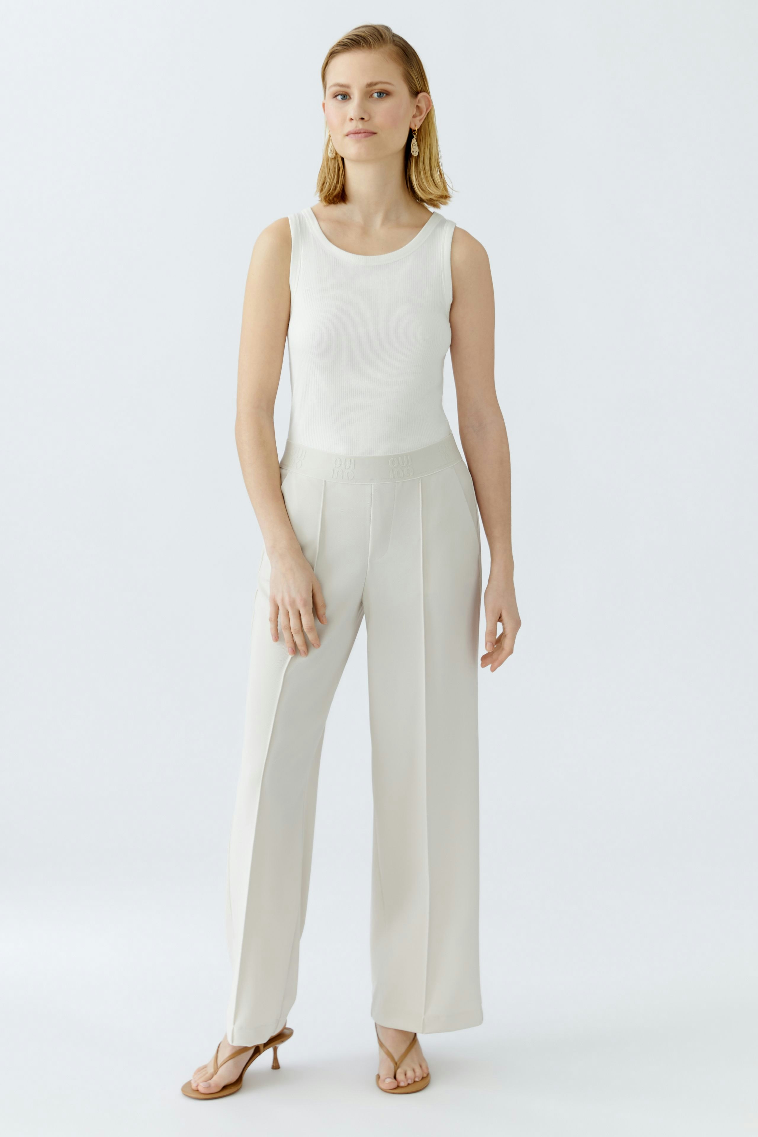 Elegante Damen-Hose: Frau in heller, weit geschnittener Hose mit elastischem Bund steht selbstbewusst.