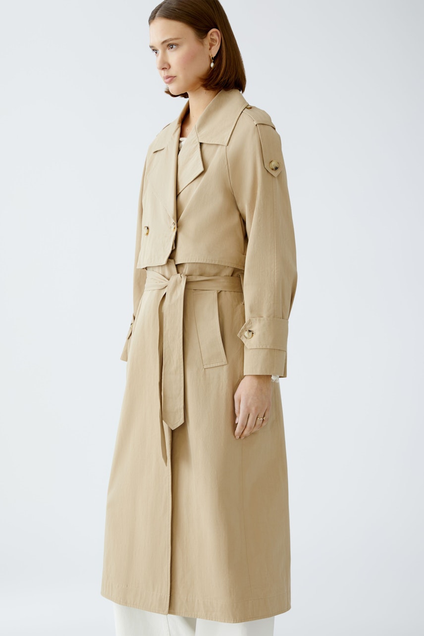 Stylish trench coat: A woman in a beige trench coat with a belted waist and classic collar.