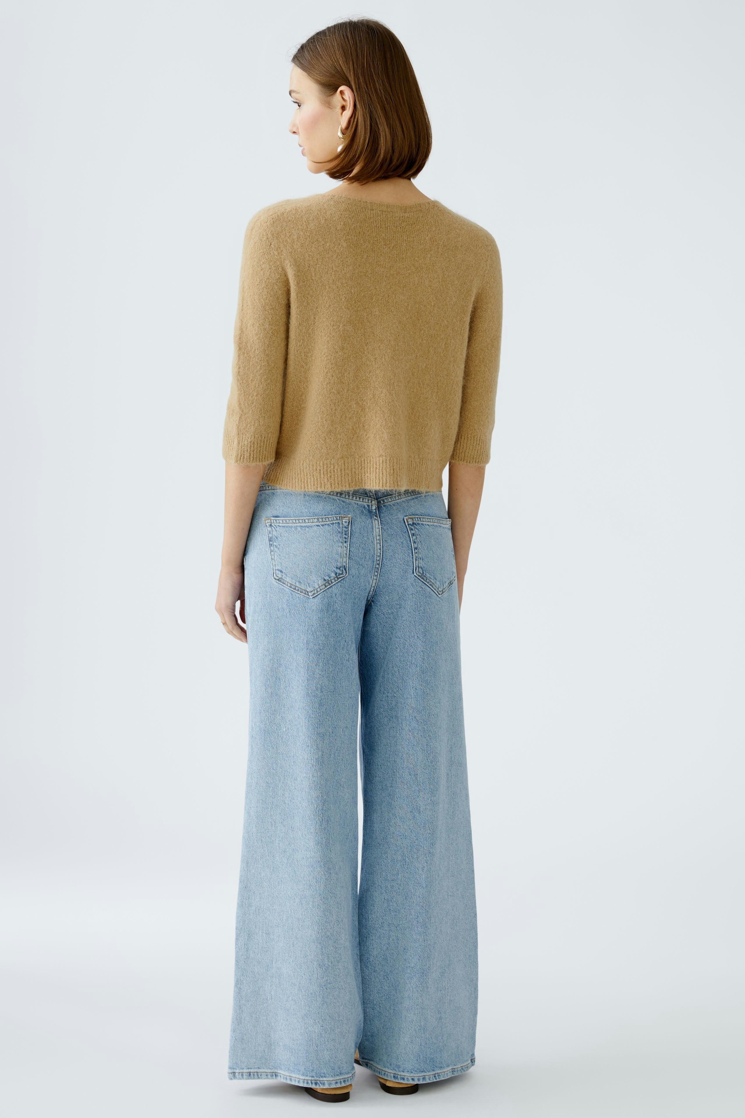 Stylish women's cardigan: A woman in a cozy beige cardigan paired with wide-leg jeans.